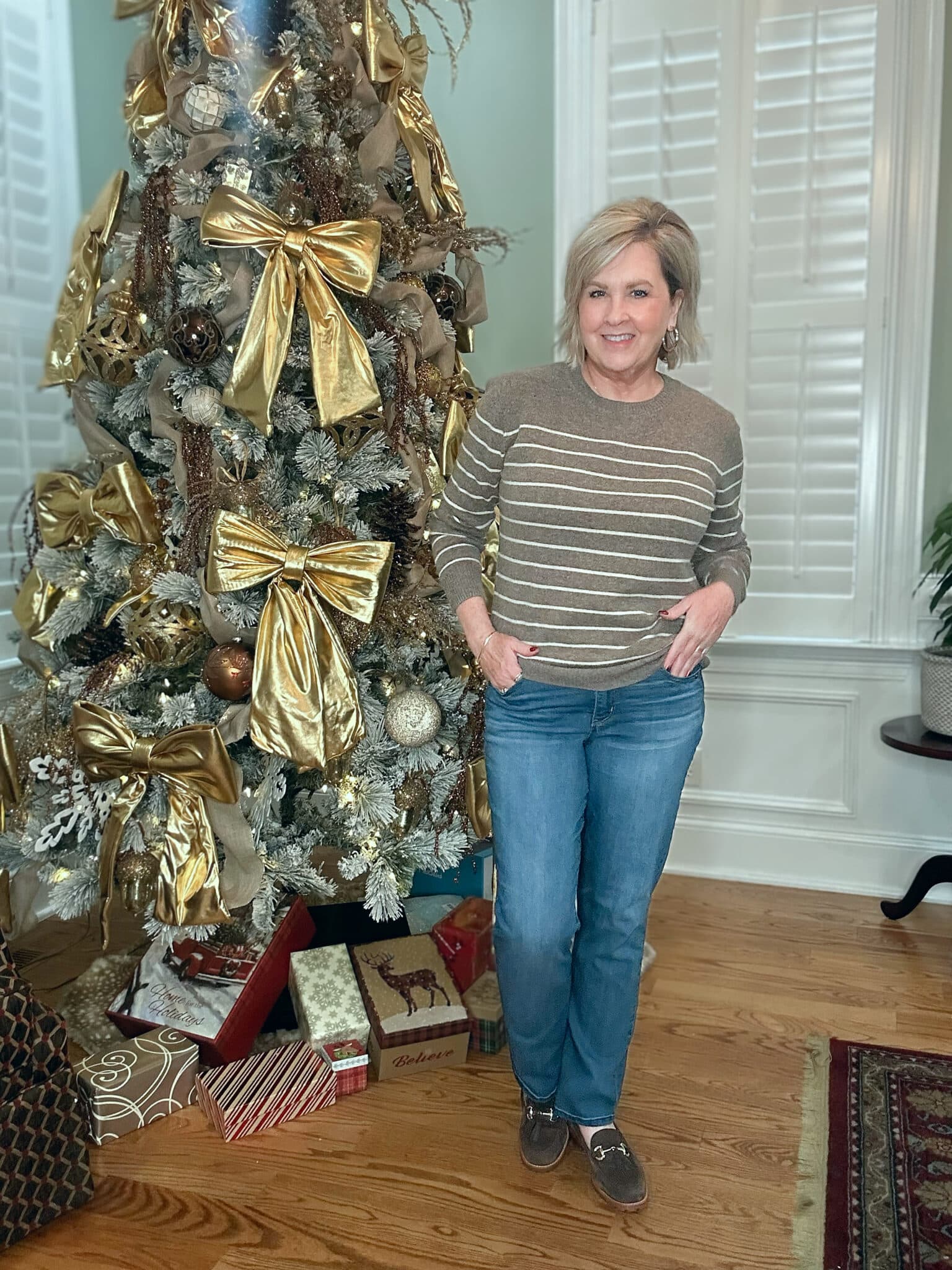 Tania Stephens is wearing a brown and white striped sweater with straight-leg jeans