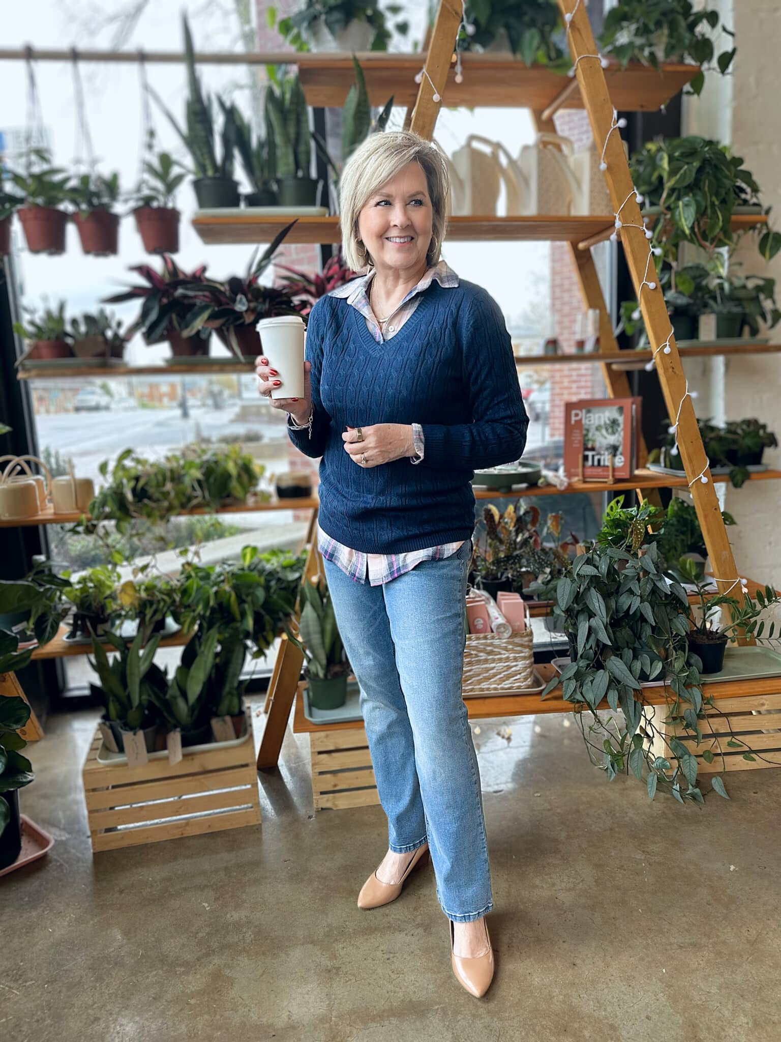 Tania Stephens is holding a cup while wearing a plaid shirt under a navy sweater and straight leg jeans from Kohl's