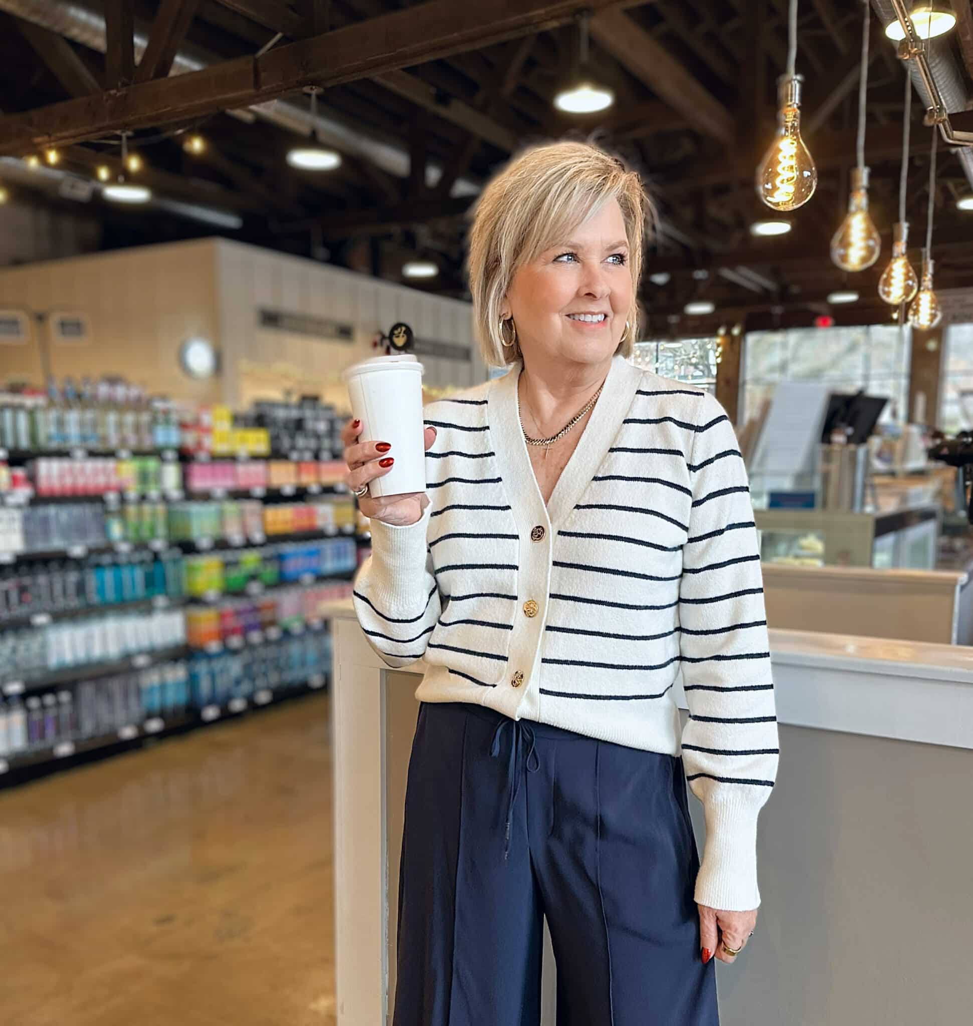 Tania Stephens is holding a cup of coffee while wearing a striped sweater from Kohl's