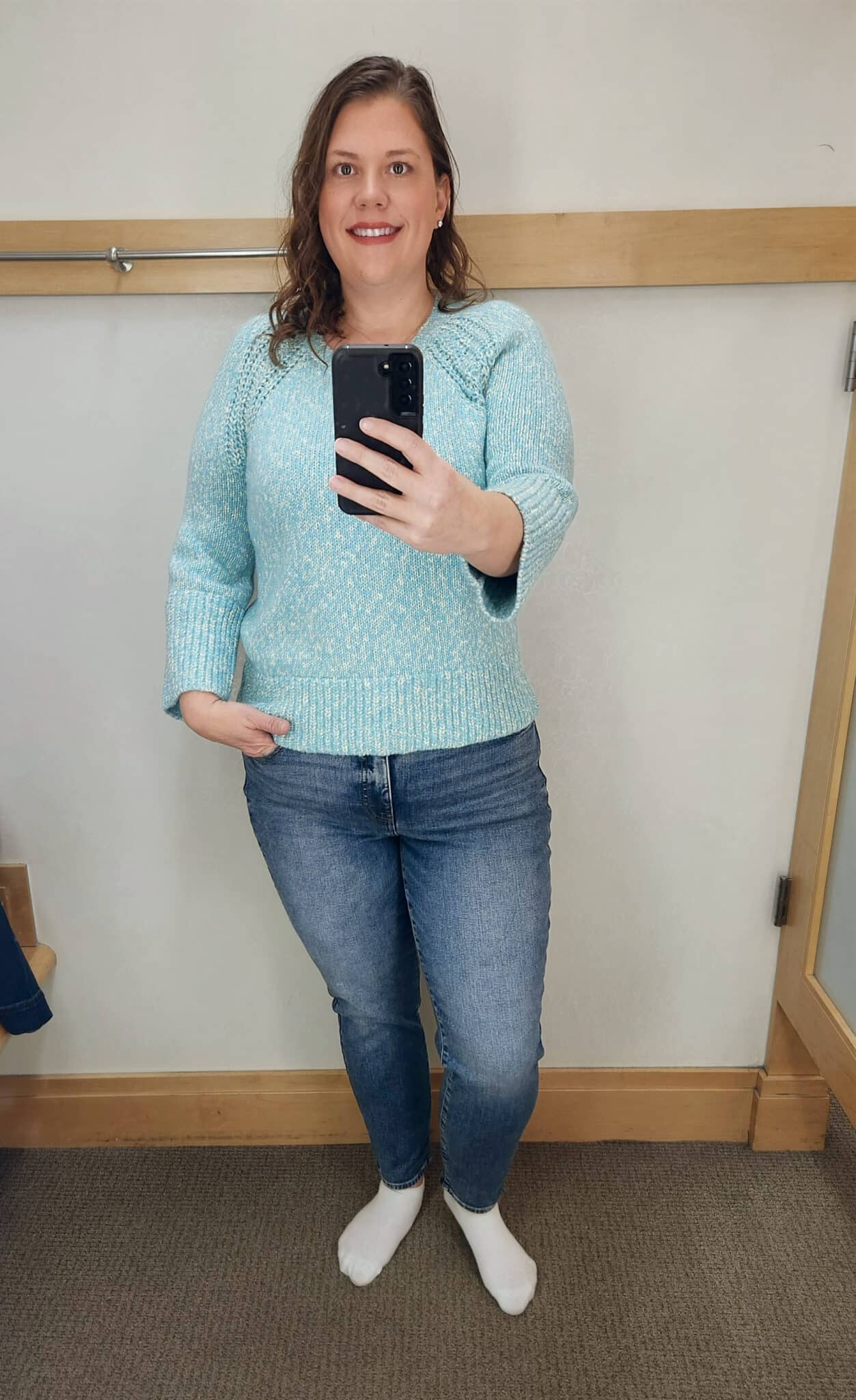 Megan is wearing a blue/green sweater and jeans