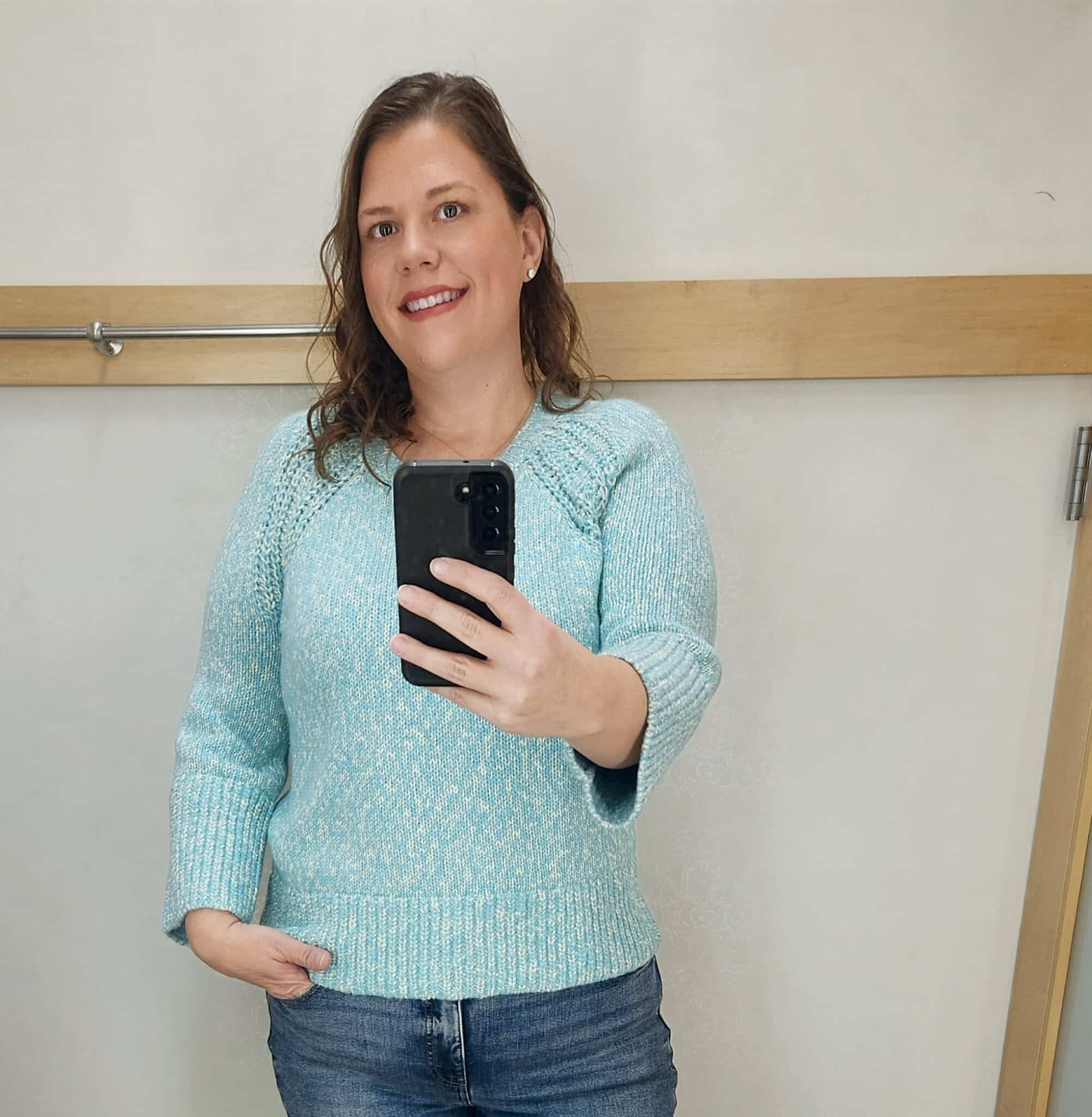 Megan is wearing a blueish sweater and jeans