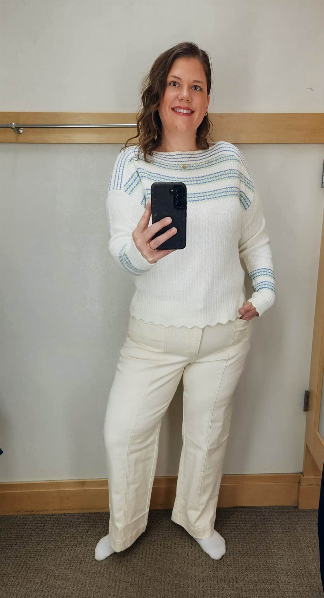 Megan is wearing an ivory striped sweater, and ivory pants