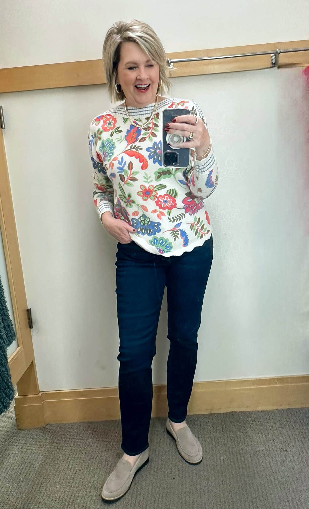 Tania Stephens is wearing a floral sweater and dark wash slim jeans