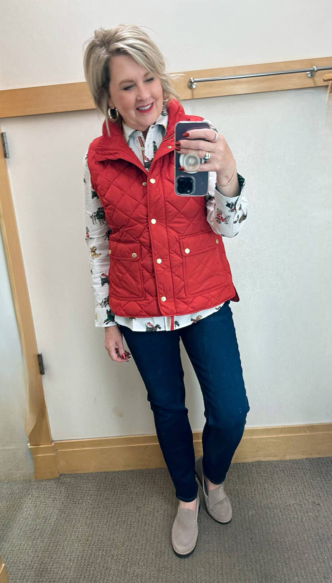Tania Stephens is wearing a button up shirt with a red puffer vest and jeans