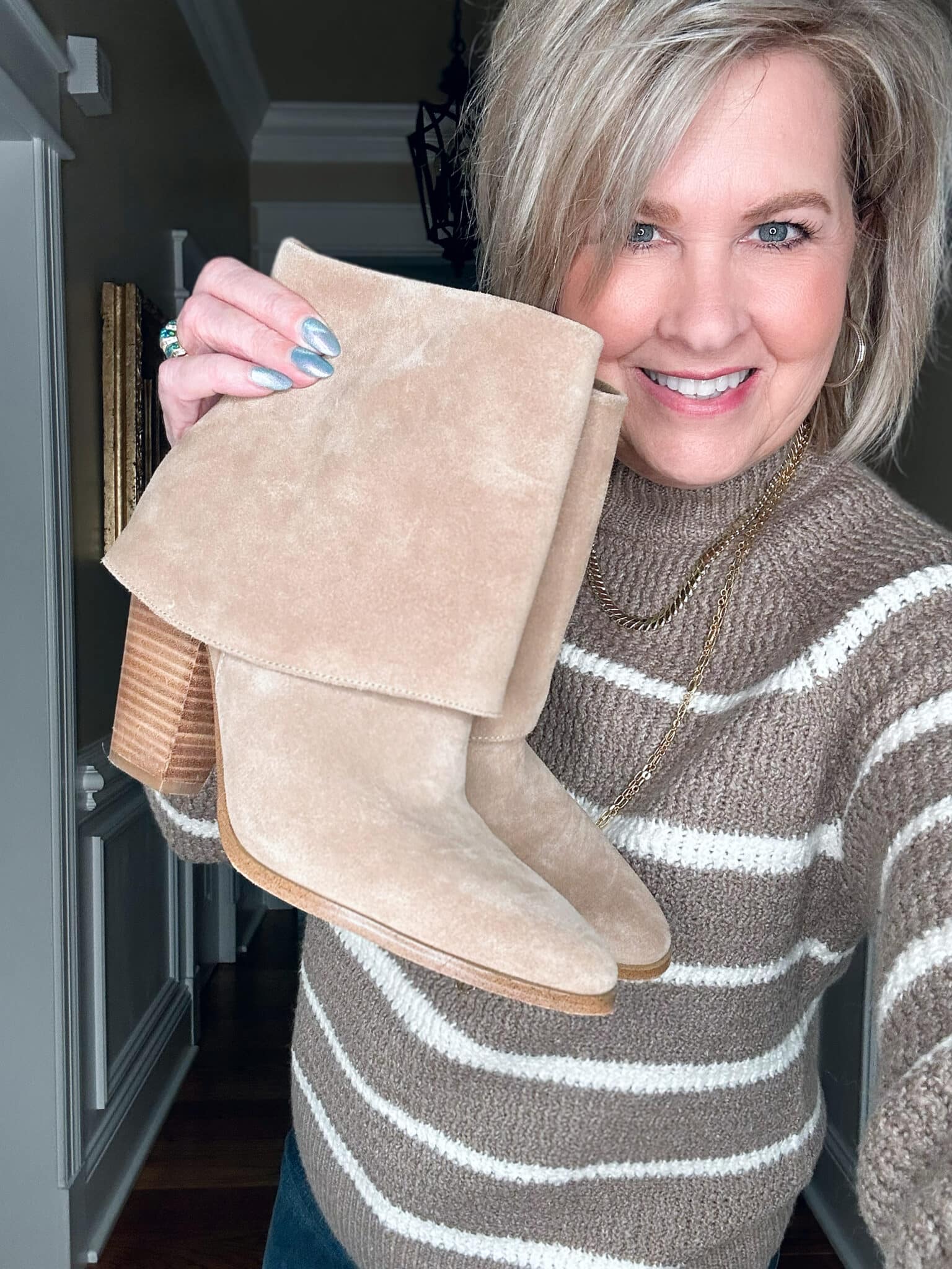 Tania Stephens is wearing a striped mocha colored sweater and ankle boots
