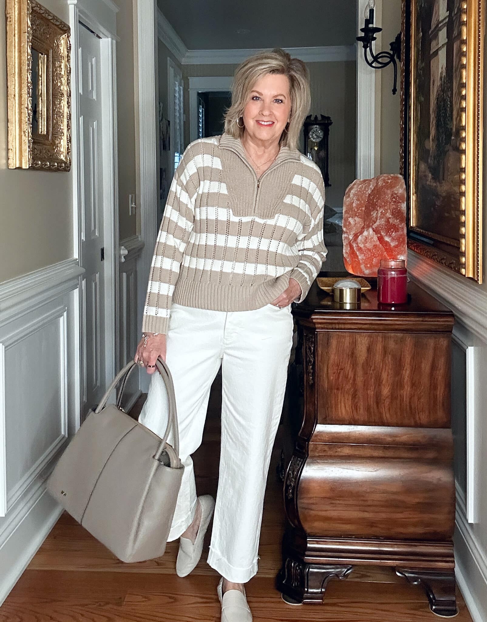 Over 50 Fashion blogger, Tania Stephens, is wearing a neutral striped sweater and white wide leg pants 