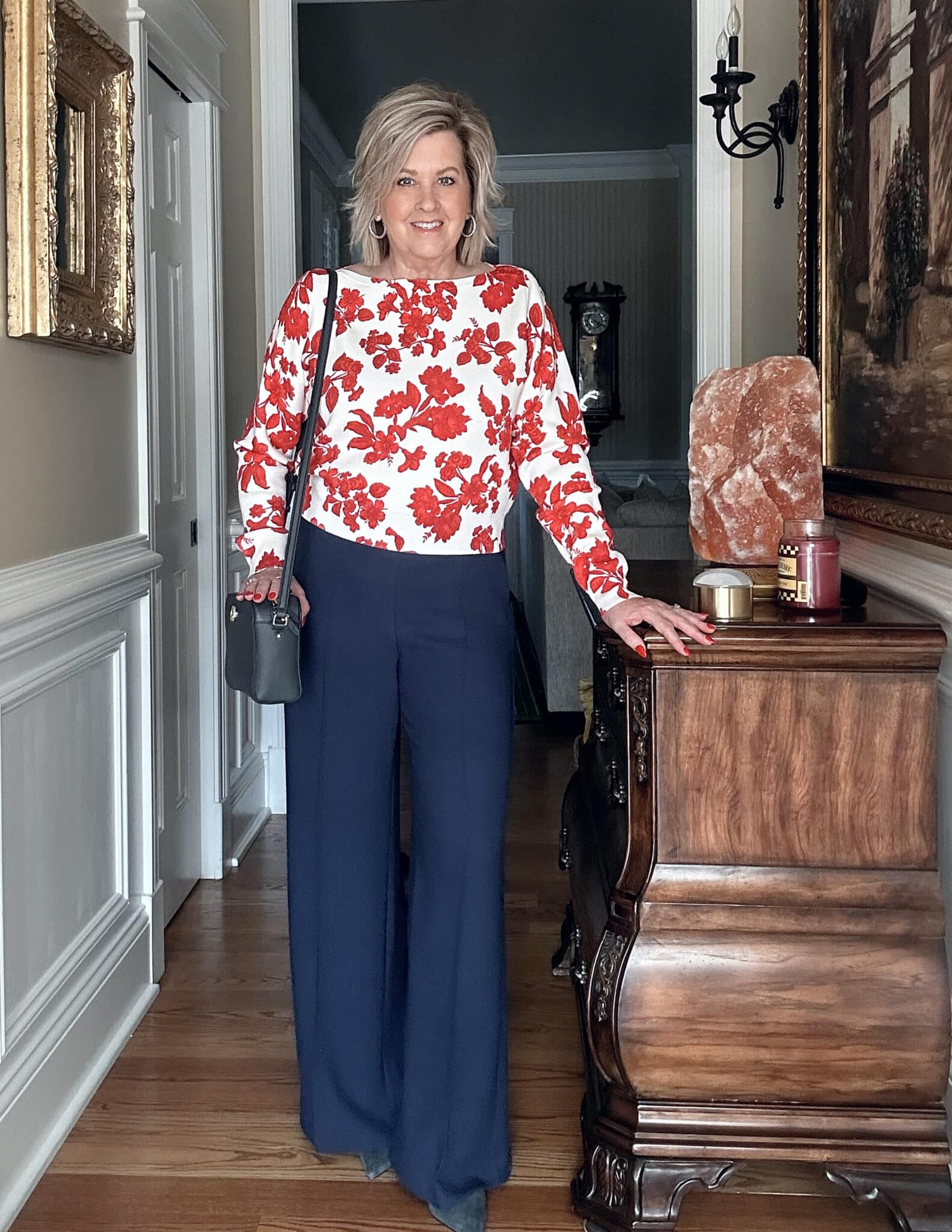 Over 50 fashion blogger, Tania Stephens is wearing a red floral sweater and navy wide leg pants pants