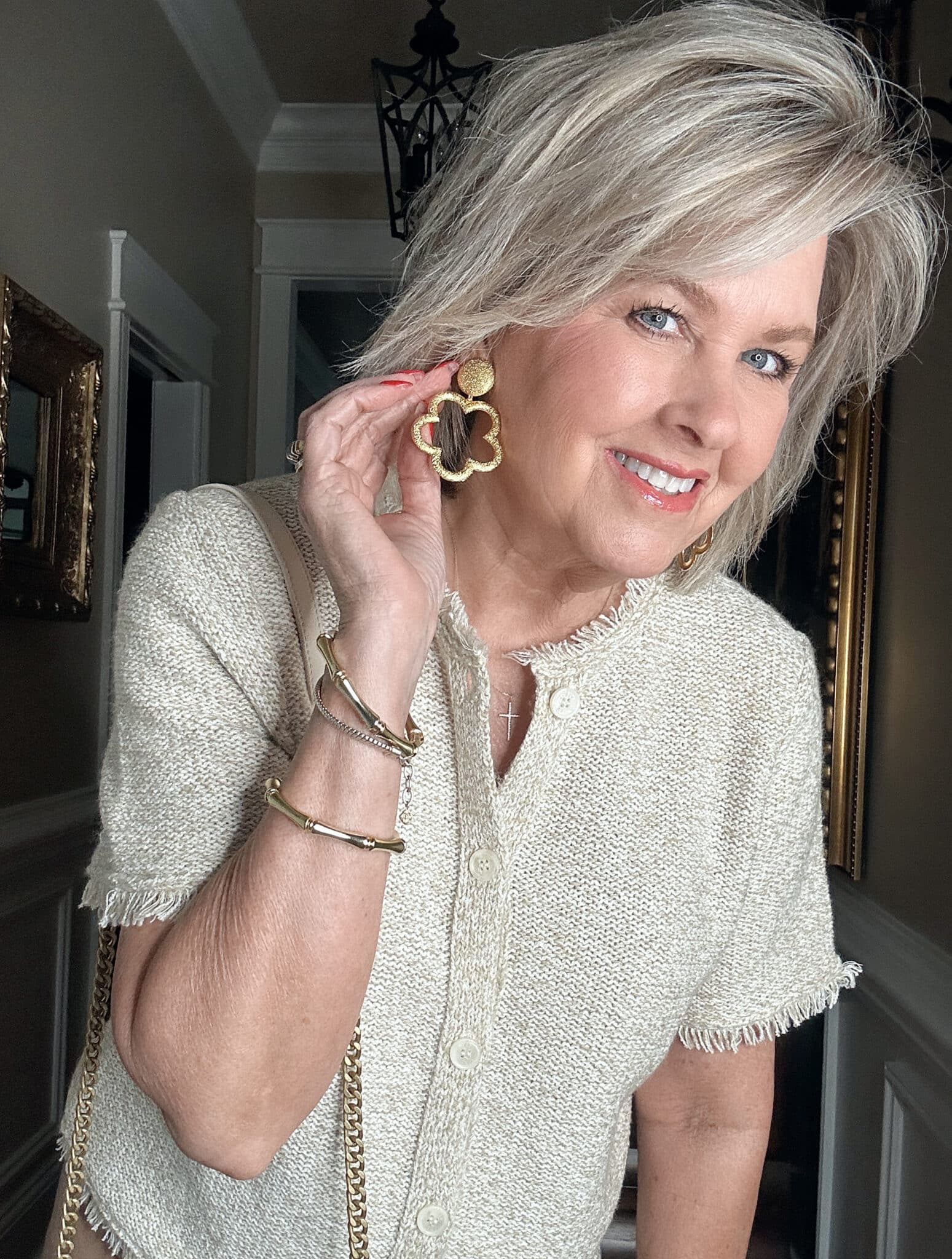 Over 50 Fashion Blogger, Tania Stephens is wearing a neutral outfit consisting of a beige fringed top with Lisi Lerch earrings