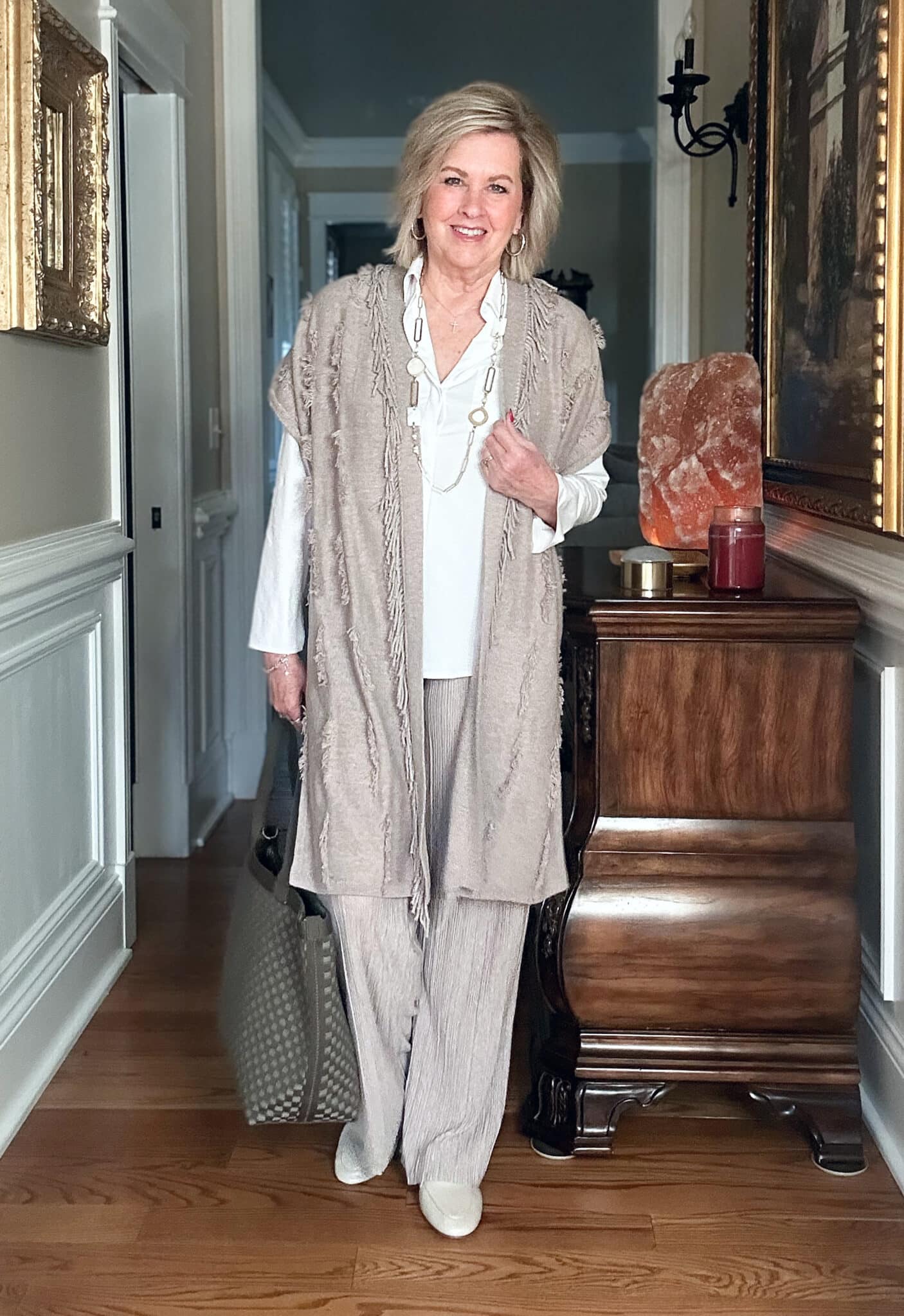 Over 50 Fashion Blogger, Tania Stephens is wearing a neutral outfit consisting of a fringed vest with beige crinkled pants from J.Jill