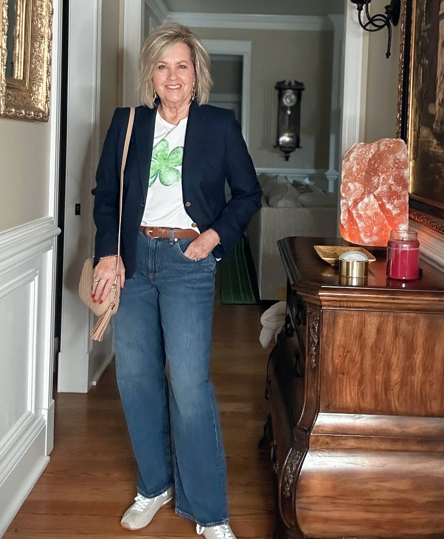 Tania Stephens, an over 50 fashion blogger, is wearing a navy blazer and jeans with a green 4 leaf clover tee.