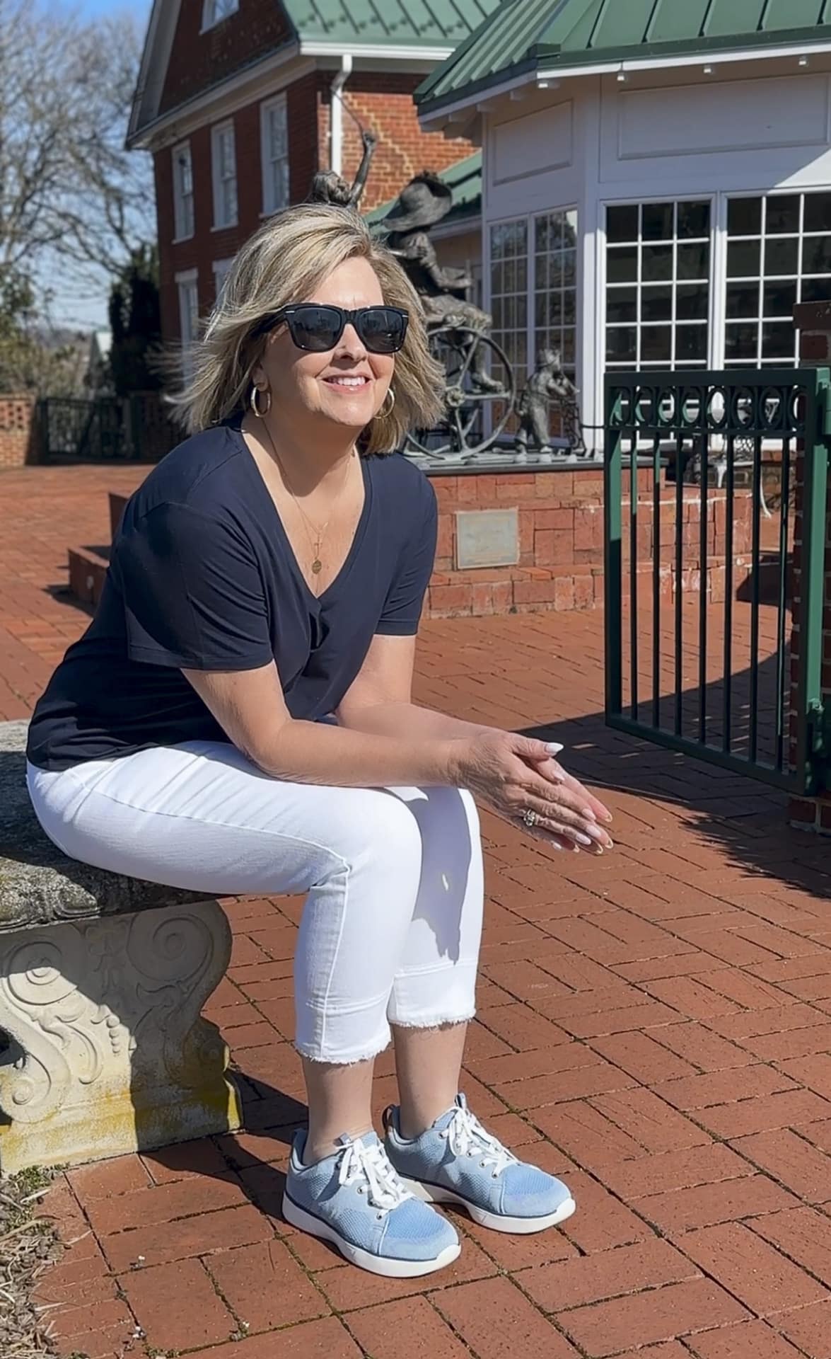Tania Stephens wearing white jeans, a navy tee, and Keds powder blue Blisswalk sneakers
