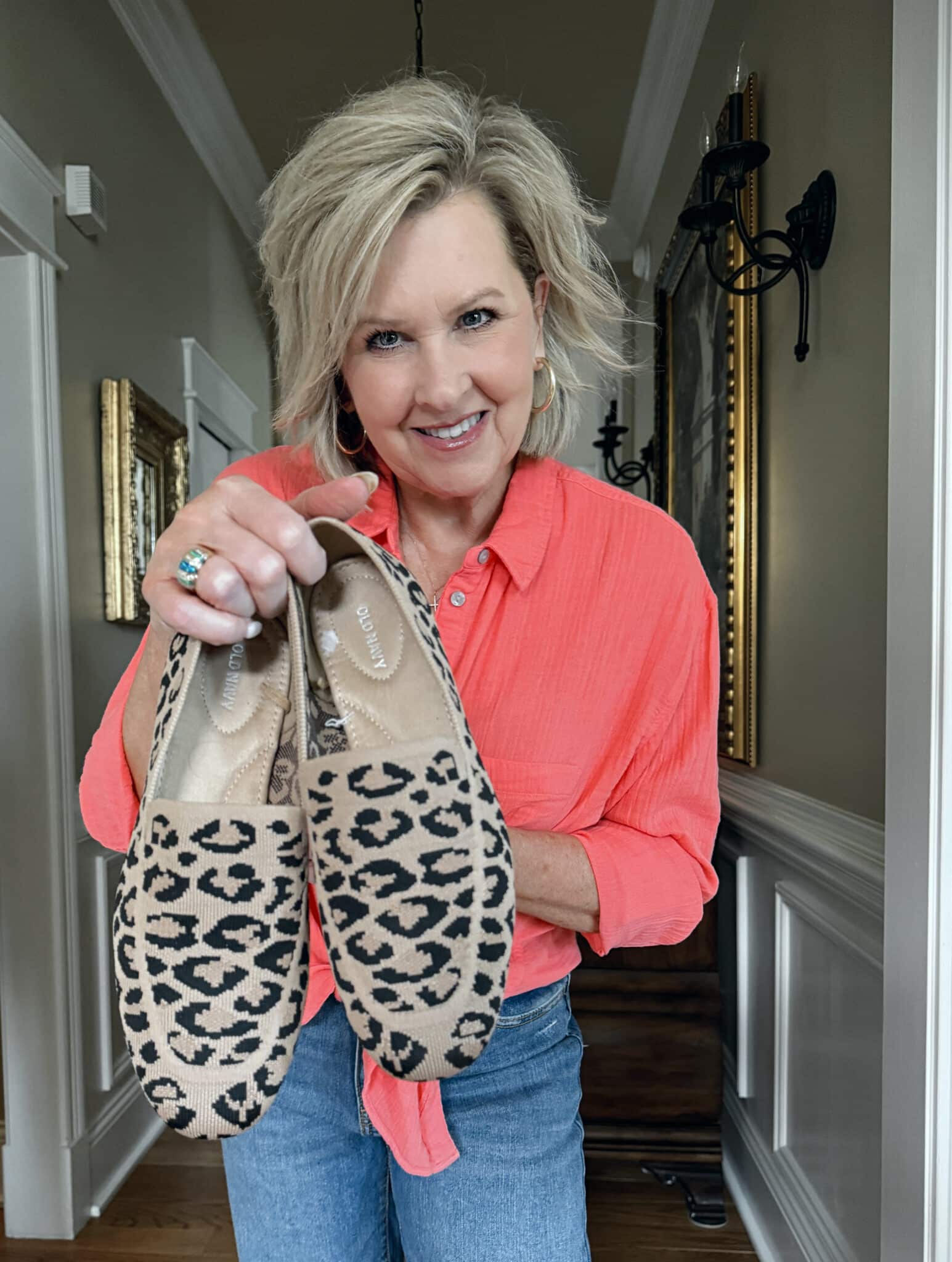 Tania Stephens is wearing a coral gauze shirt and holding leopard print shoes from Walmart