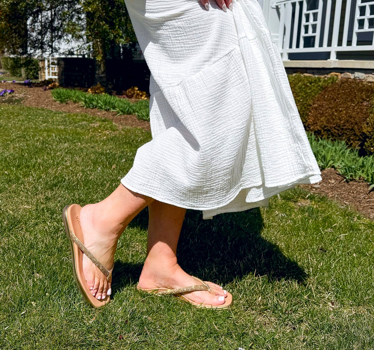 Tania Stephens wearing 2025 Spring styles of a white  gauze dress and gold sparkly sandals from Nordstrom Rack
