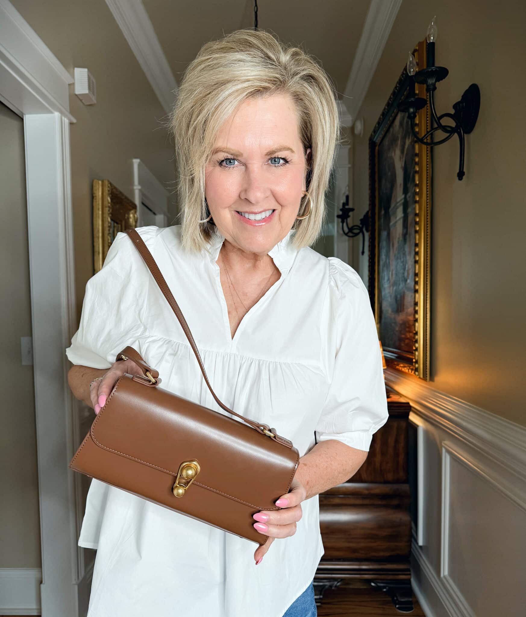 Tania Stephens is wearing a white top with a brown turnlock handbag from Amazon