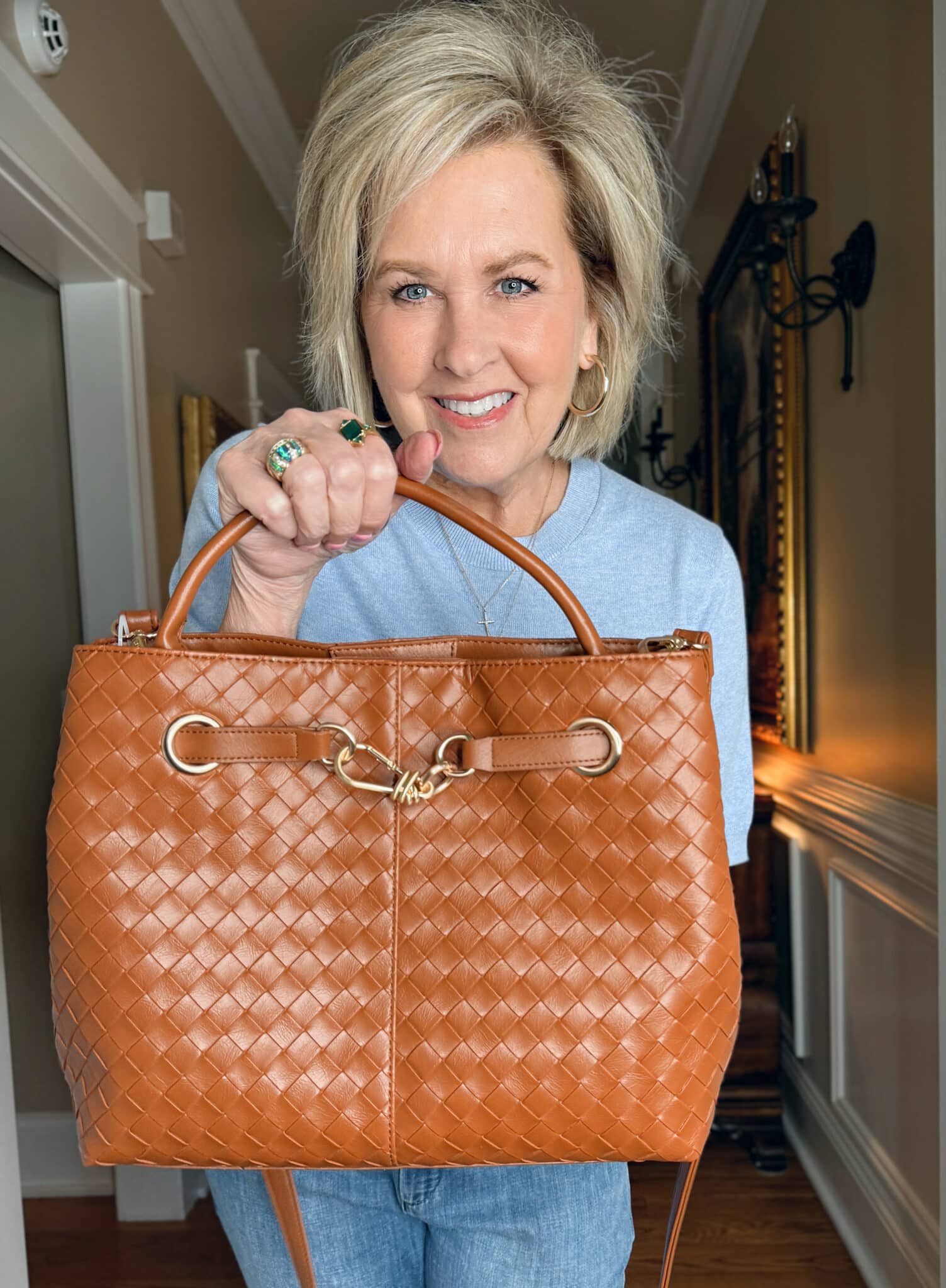 Tania Stephens is wearing a light blue sweater with a woven handbag