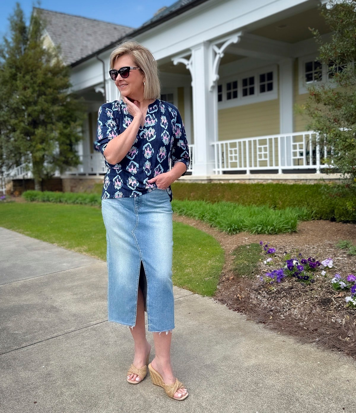 Woman in an ikat print blouse and light-wash denim midi skirt with wedge sandals