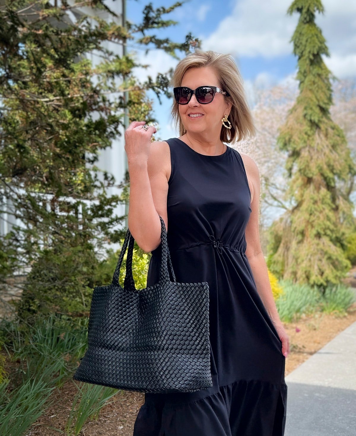 a woman wearing sunglasses and a black dress for a casual spring day