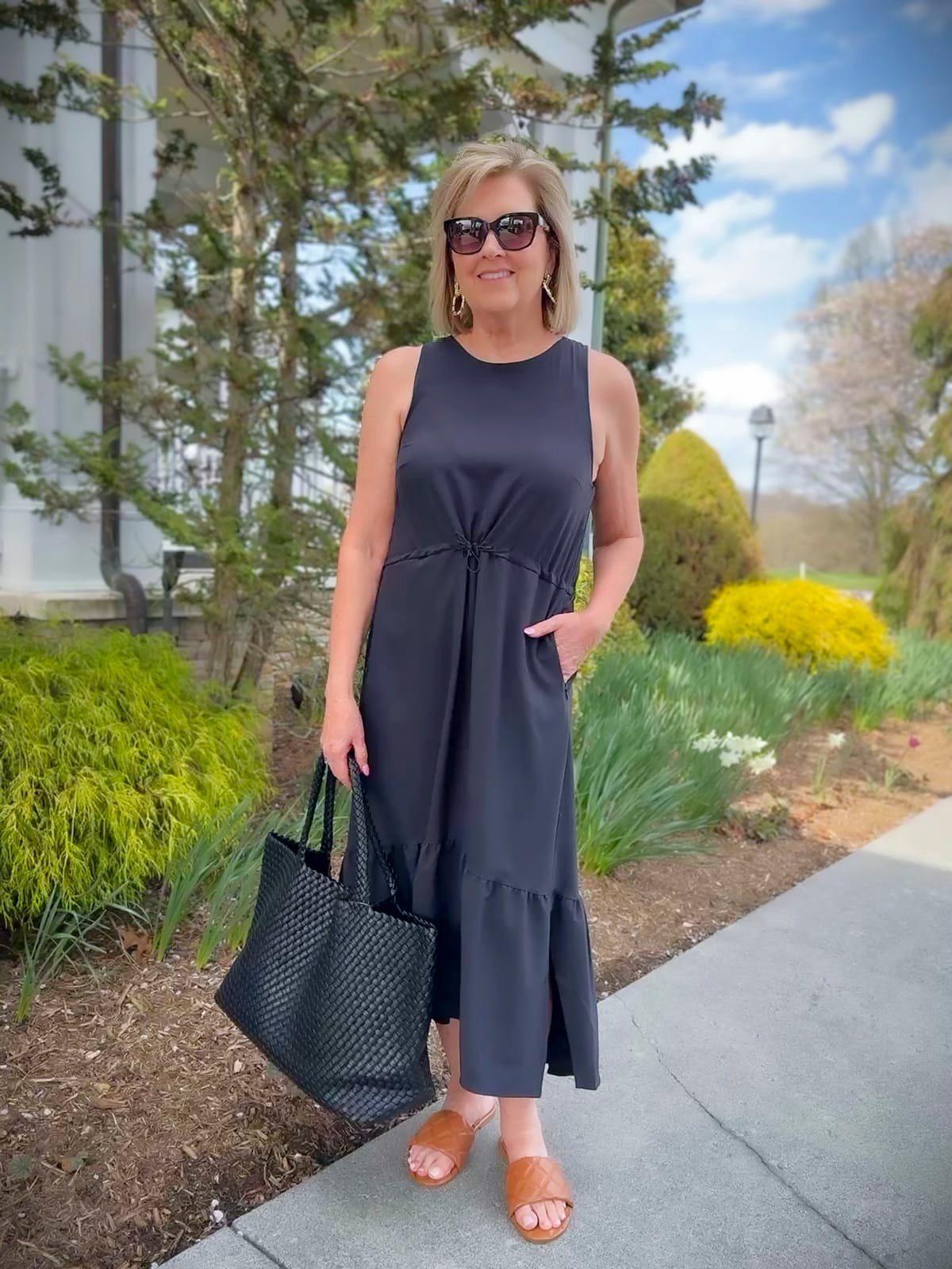 a woman in a casual black dress, brown sandals on a beautiful spring day