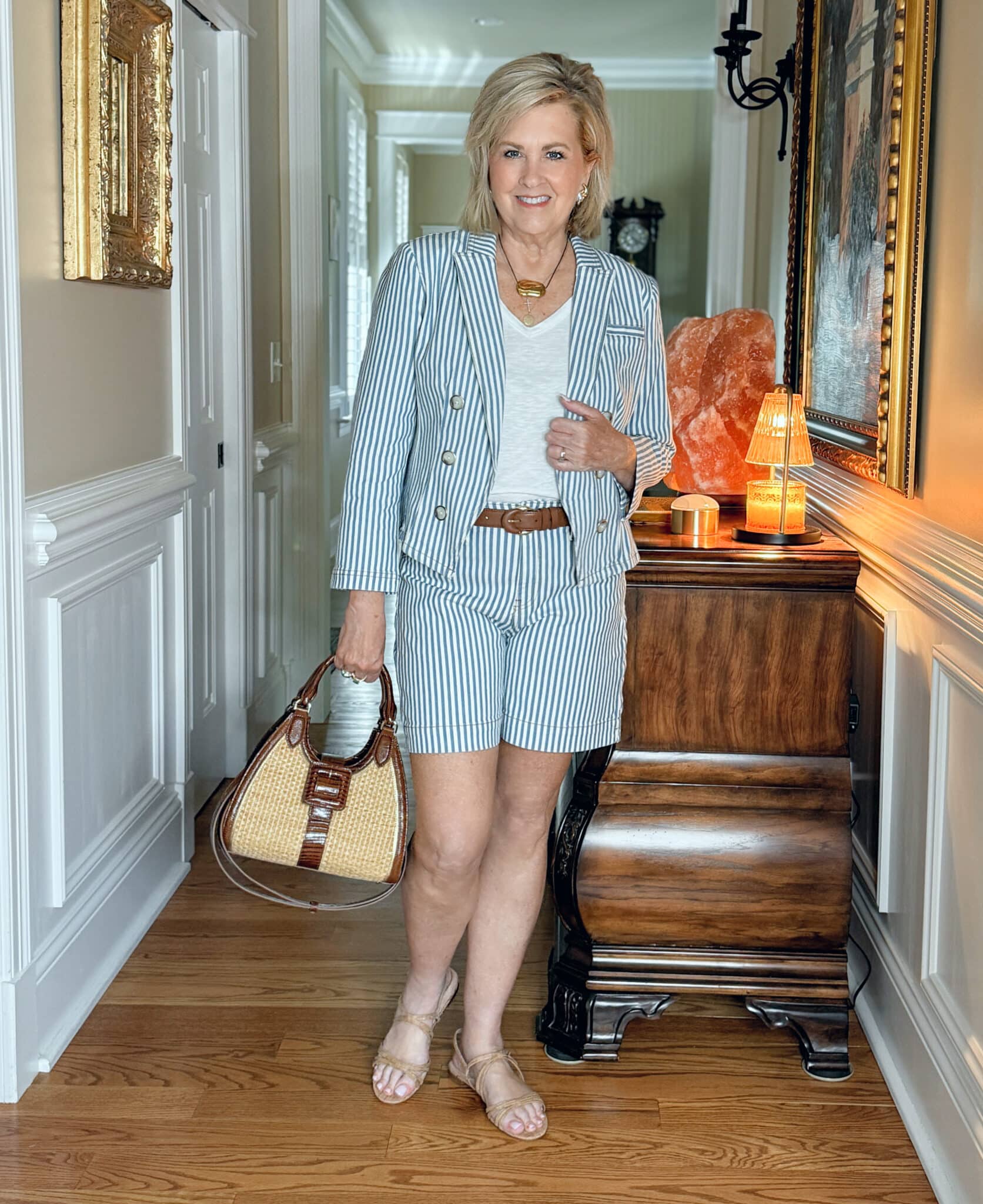 Woman over 50 wearing a matching striped blazer and trouser shorts with a white tee, cork sandals, and a structured satchel—perfect for a polished weekend look.