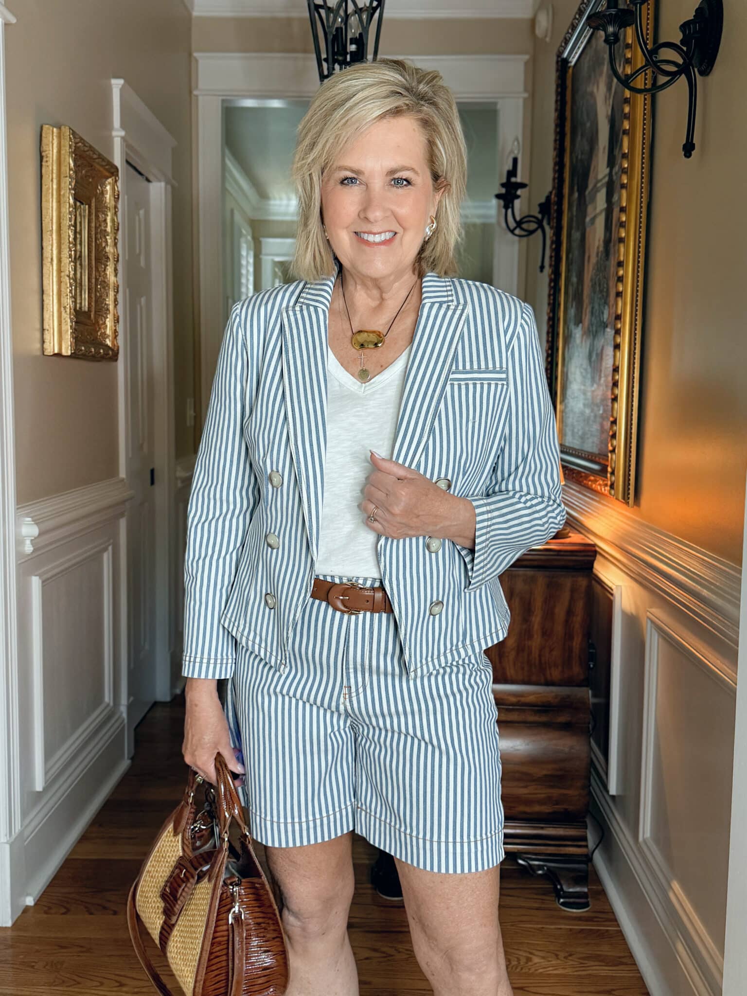 Woman over 50 wearing a matching striped blazer and trouser shorts with a white tee