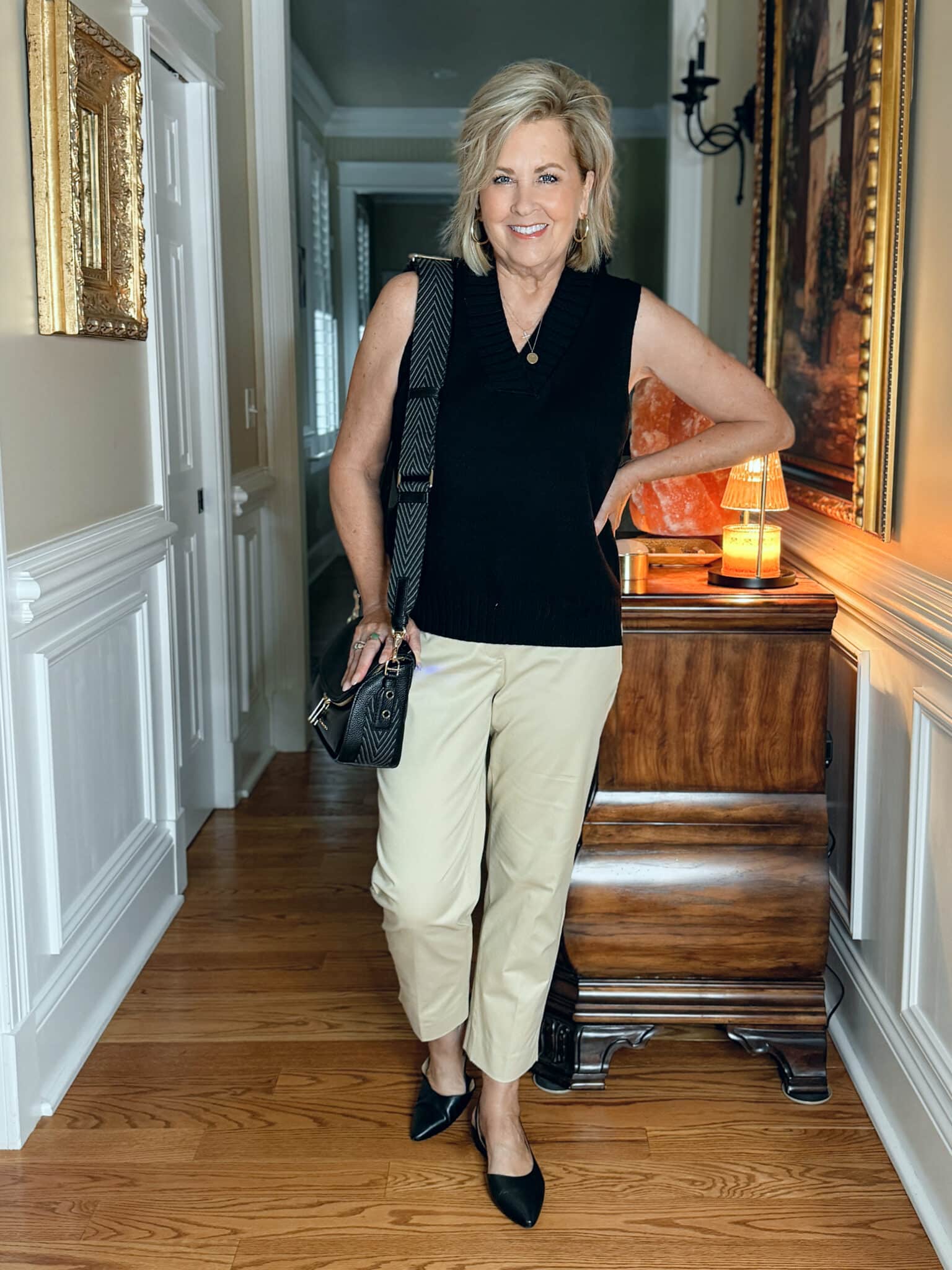 Woman wearing a long black sweater vest for summer with beige chino pants