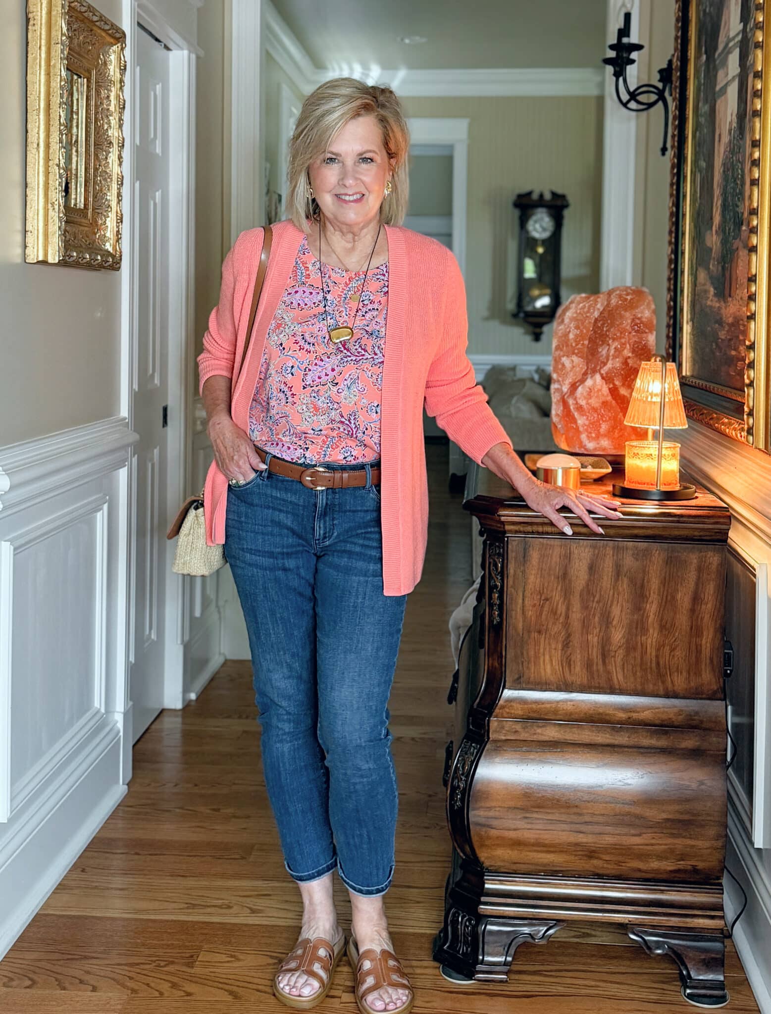 woman wearing a J.Jill a summer outfit with a coral cardigan, coral printed top, and jeans