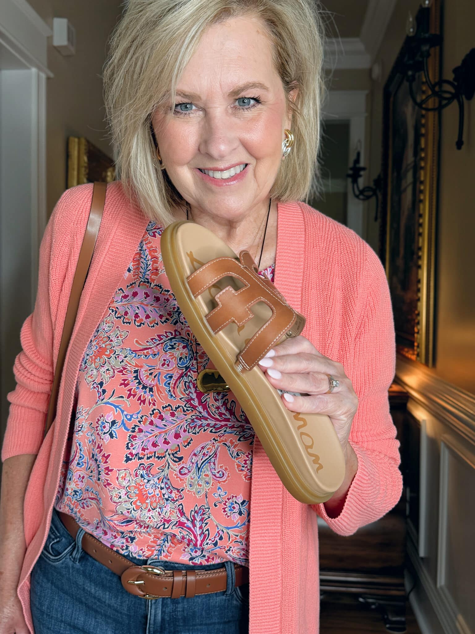 woman wearing a J.Jill a summer outfit with a coral cardigan, a coral printed top, and sandals
