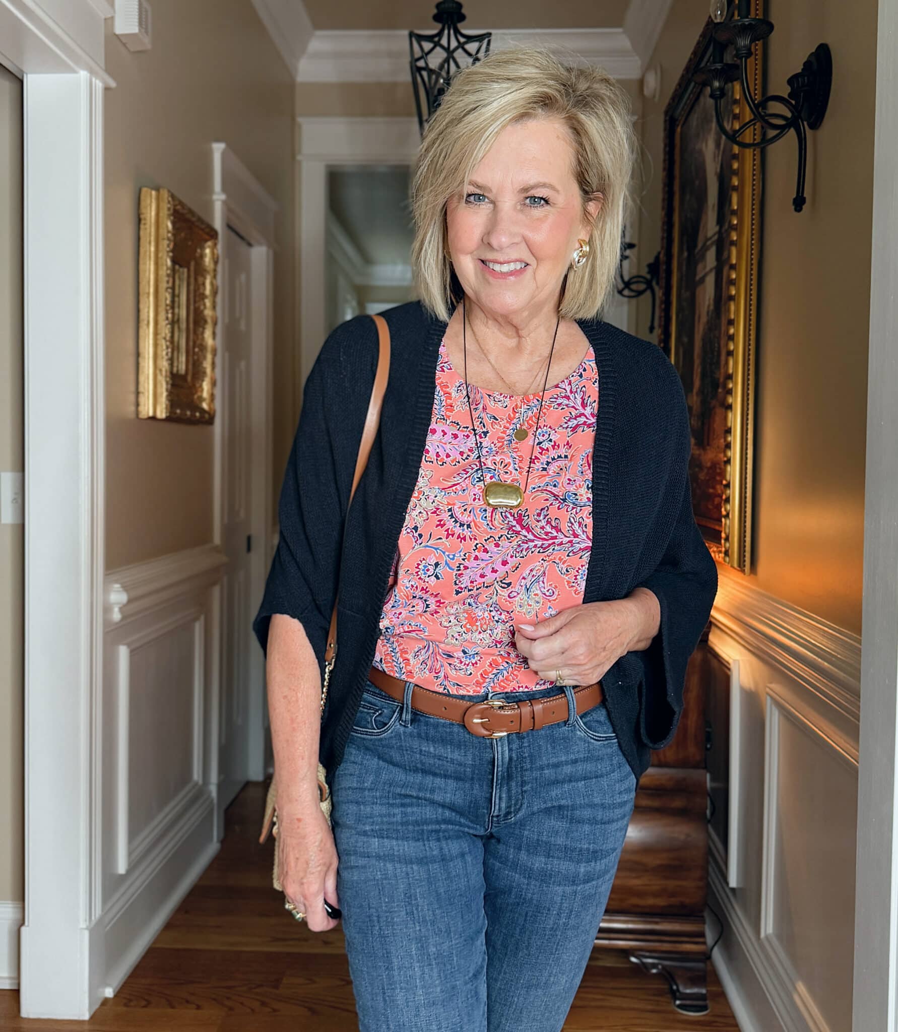 woman wearing a J.Jill a summer outfit with a navy cardigan, orange printed top, and jeans