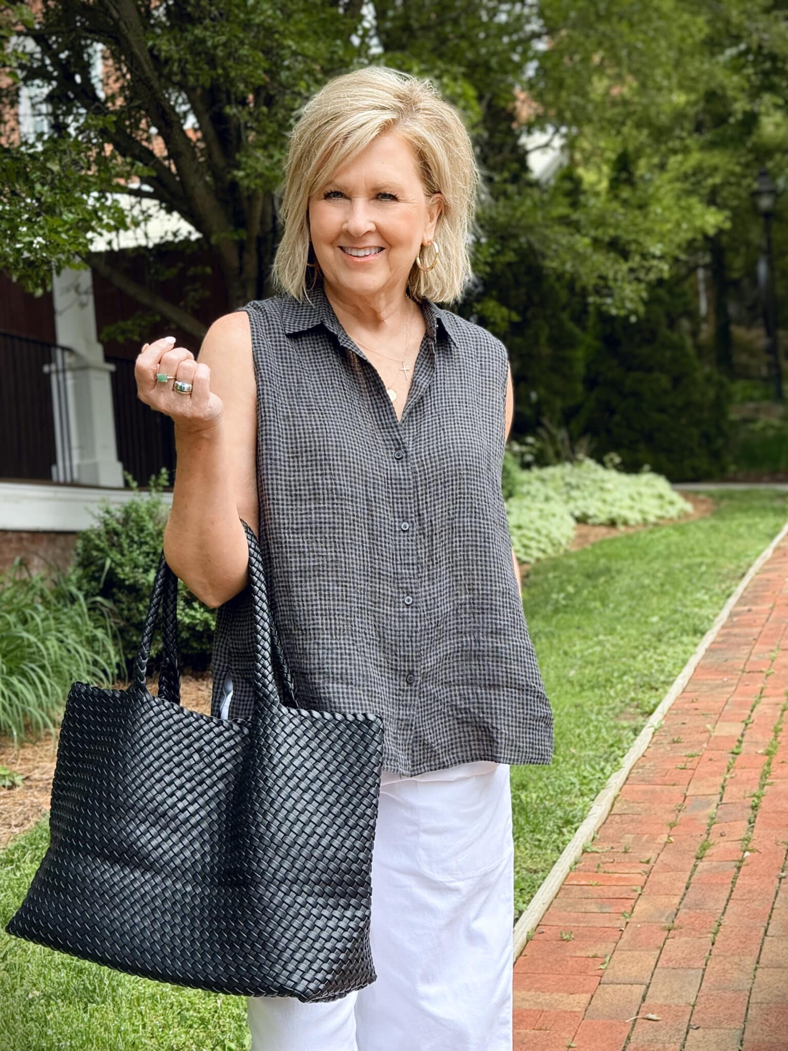 woman wearing a checked sleeveless top and a black woven tote
