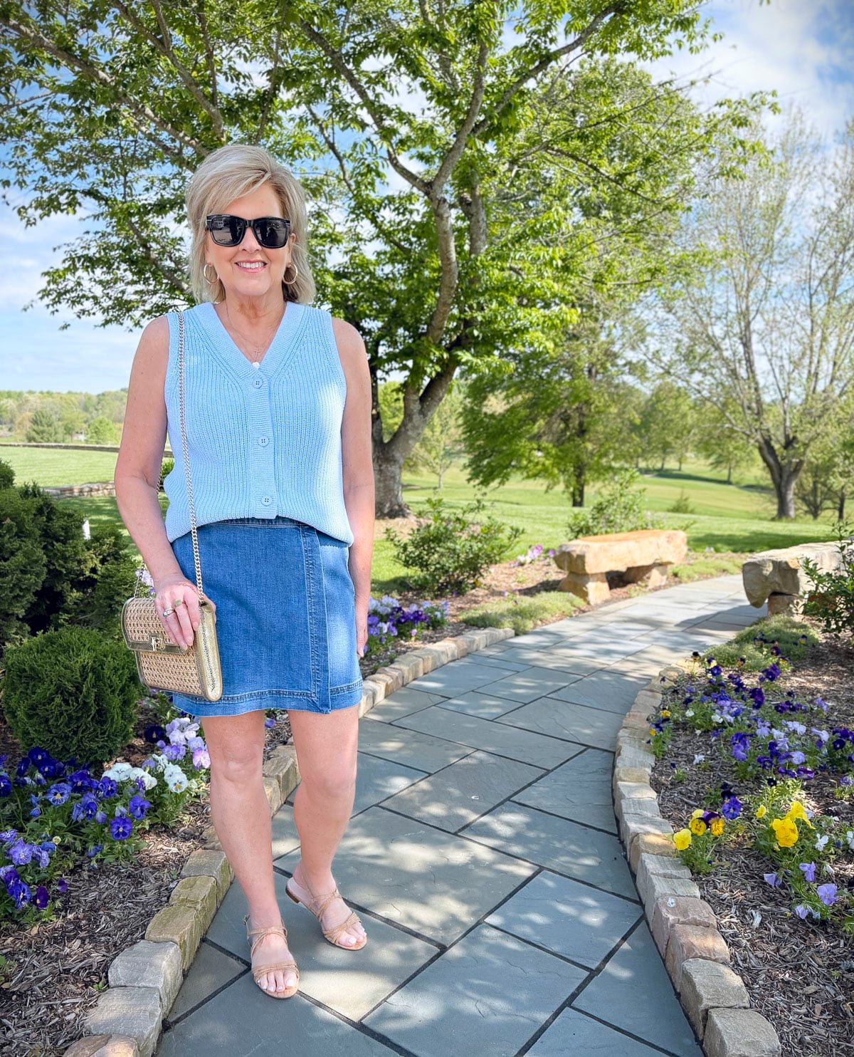Marl sweater vest styled with a denim skort and cork sandals, holding a rattan clutch—perfect for casual summer days