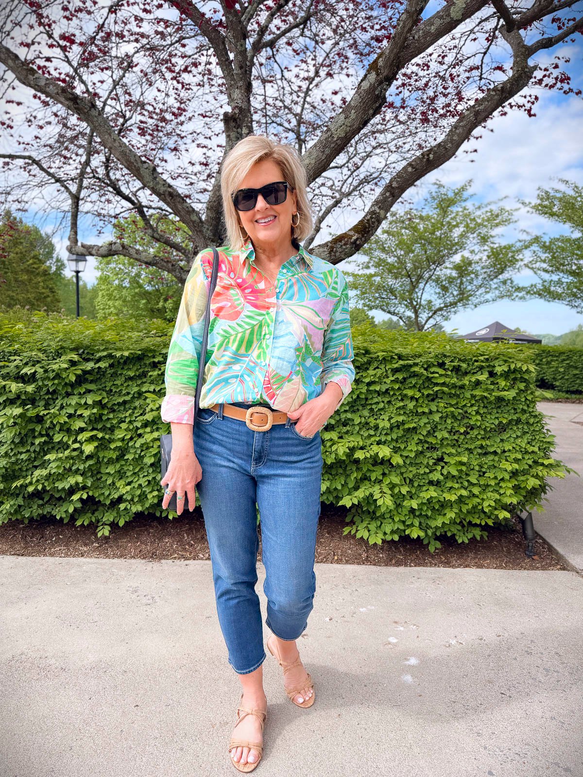 Woman wearing a white button-down shirt, raffia belt, and cropped jeans from Talbots Summer 2025 collection with crossbody bag and cork sandals