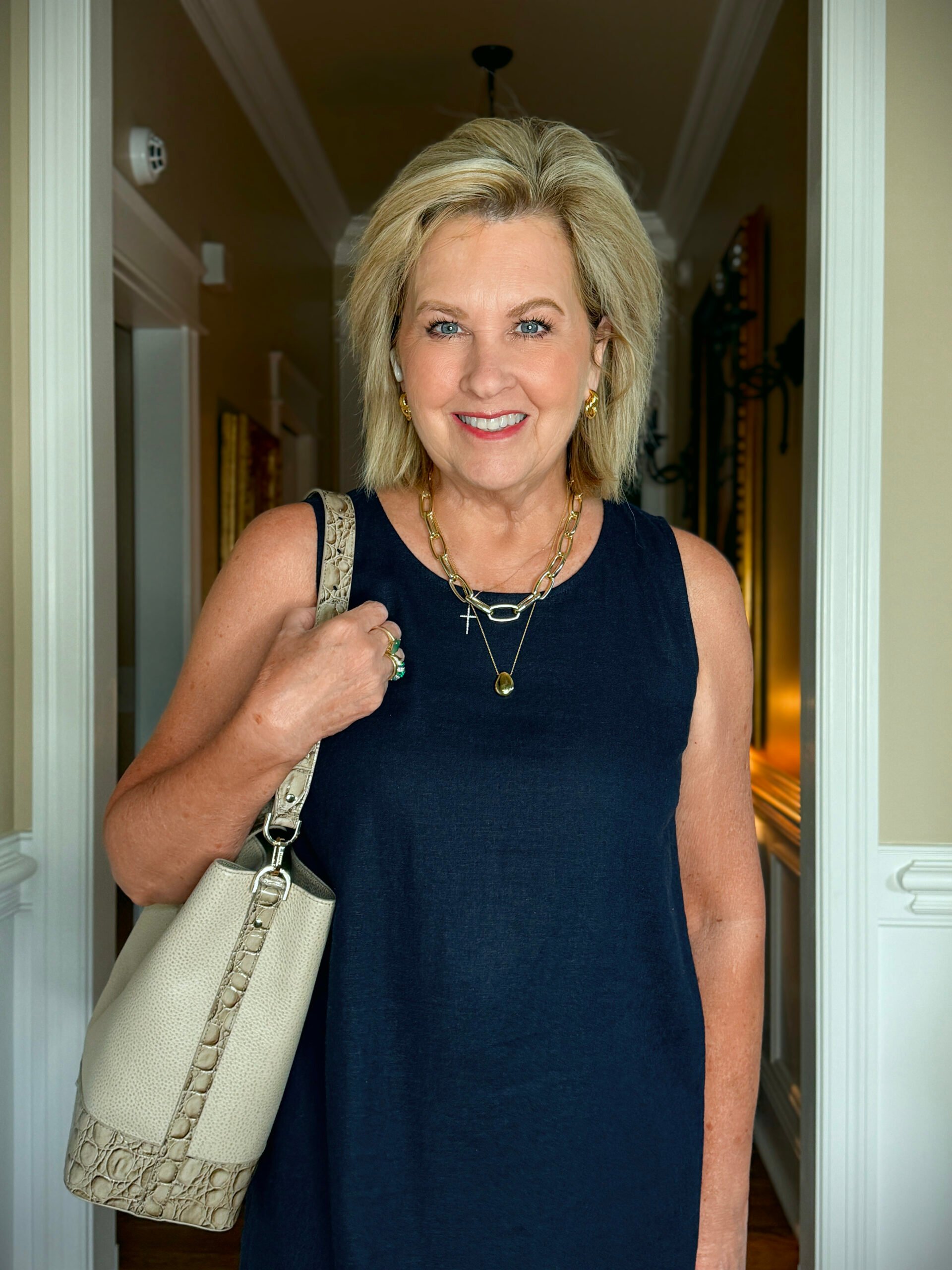 Tania in a navy linen dress with gold jewerly and a neutral bag for accessories