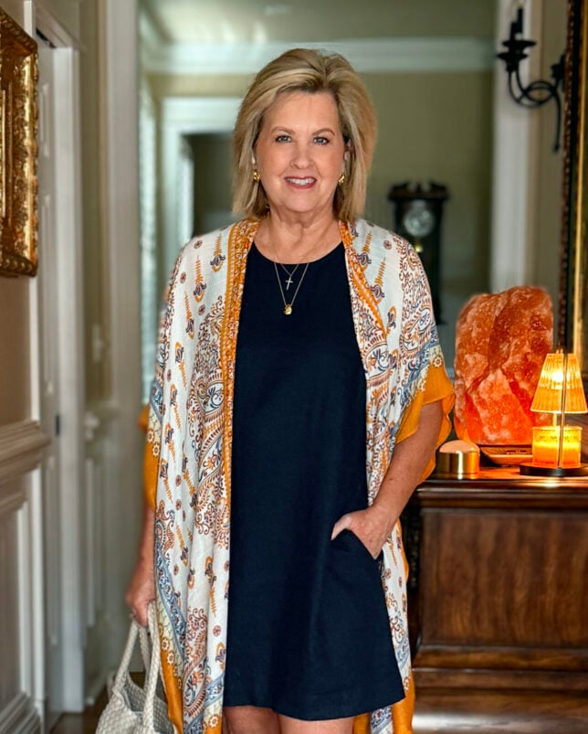 Tania wearing a versatile navy linen shift dress with a colorful ruana 