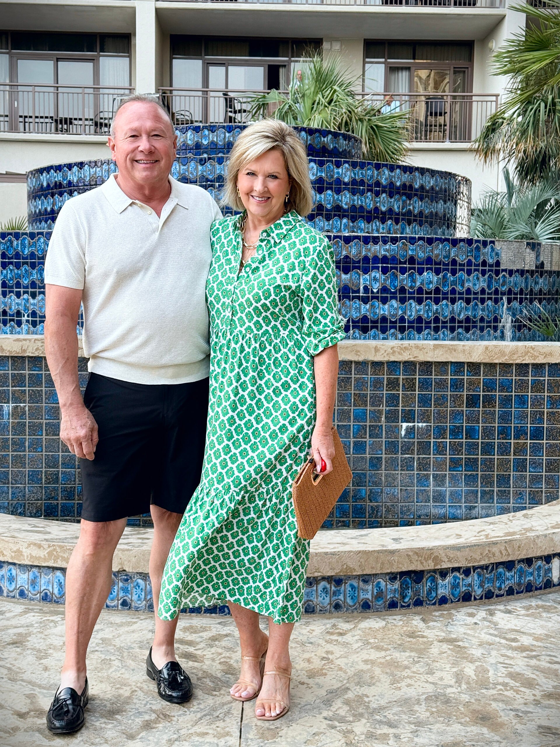 Handsome man in oatmeal cotton polo sweater and black shorts giving his best GQ pose next to a glowing beachside fountain.