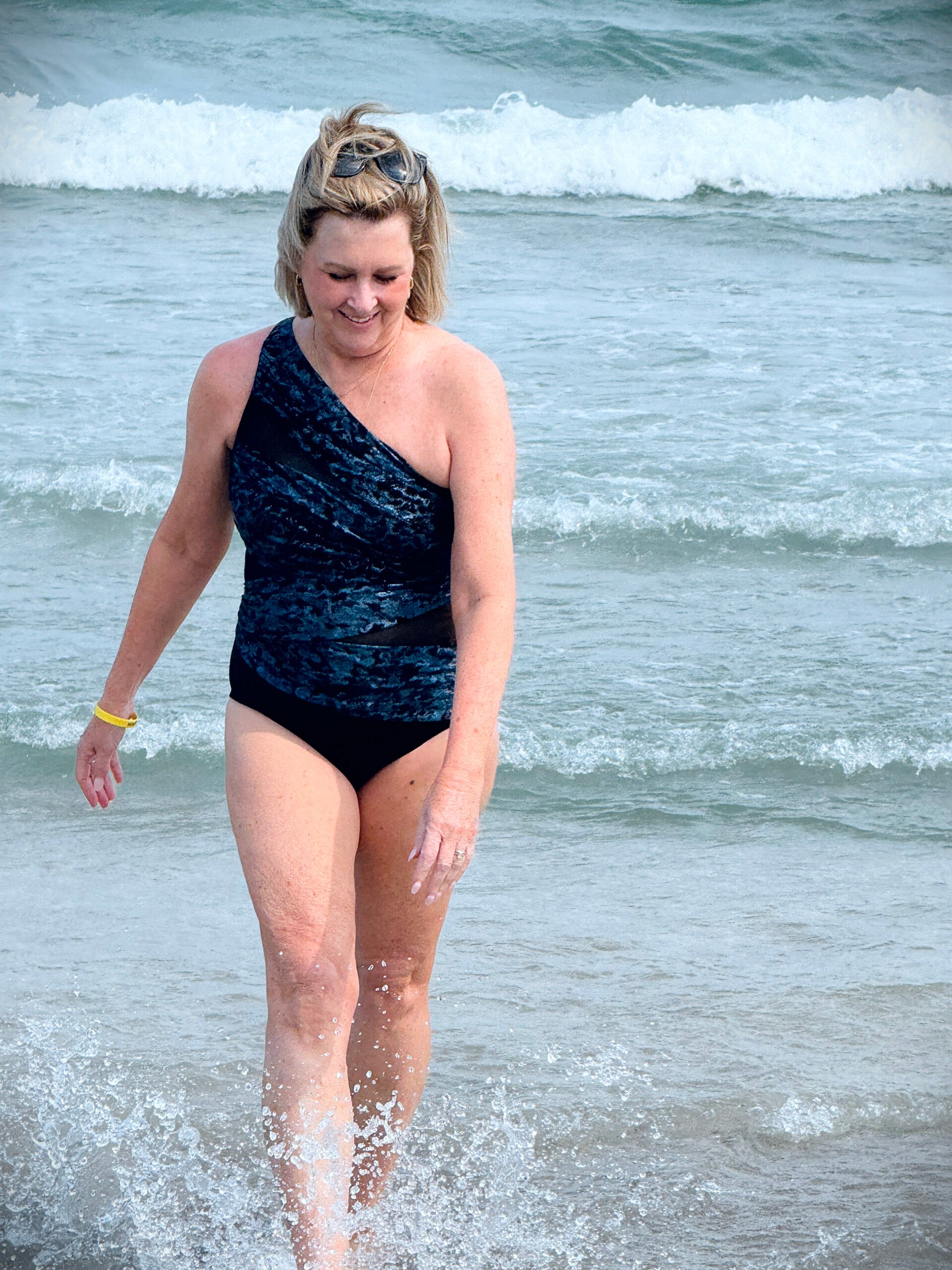 Tania wearing a one shoulder swimsuit  in the ocean while on vacation at the beach