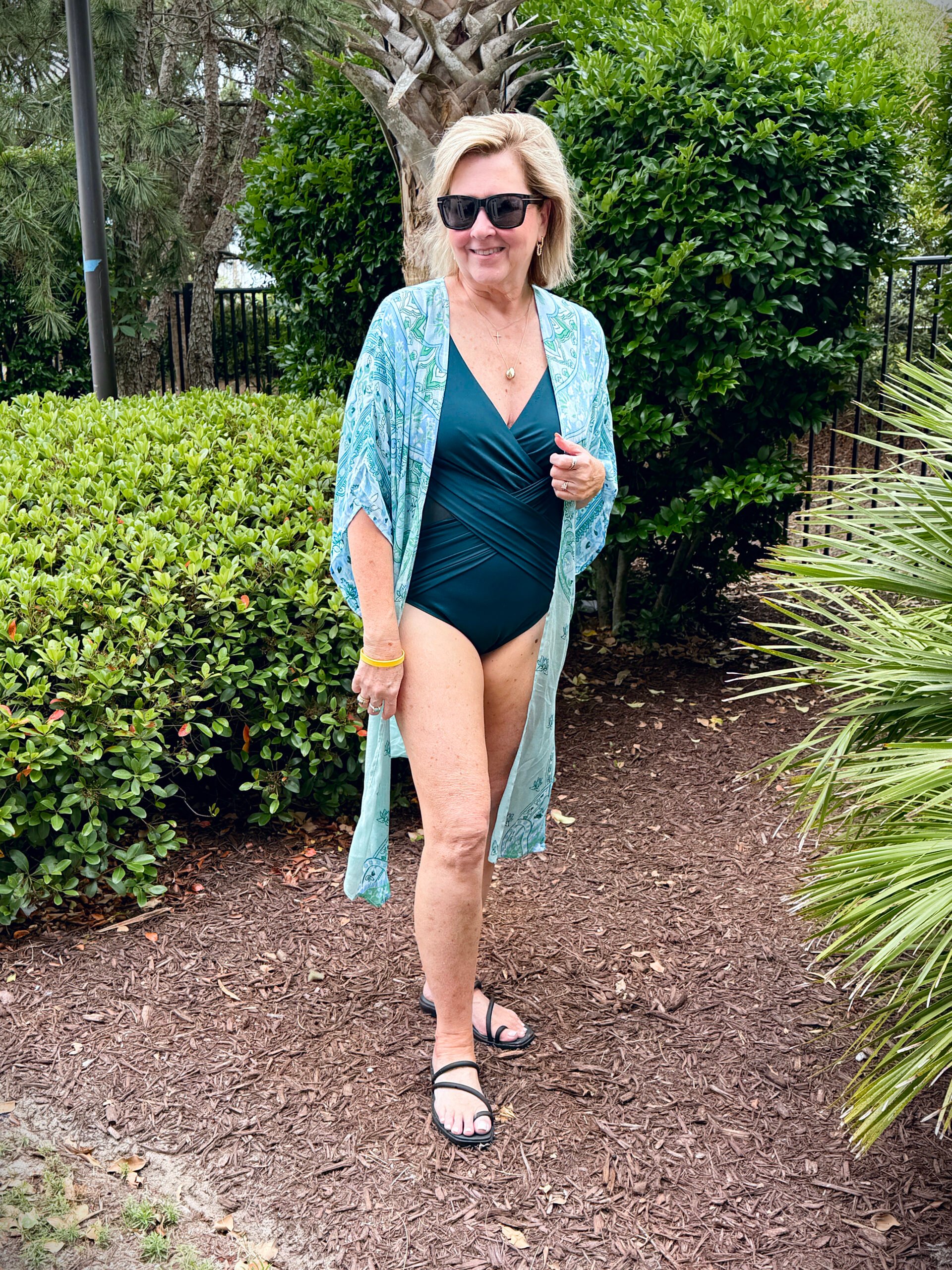 Tania wearing a dark green miraclesuit with a  kimono while on vacation at the beach