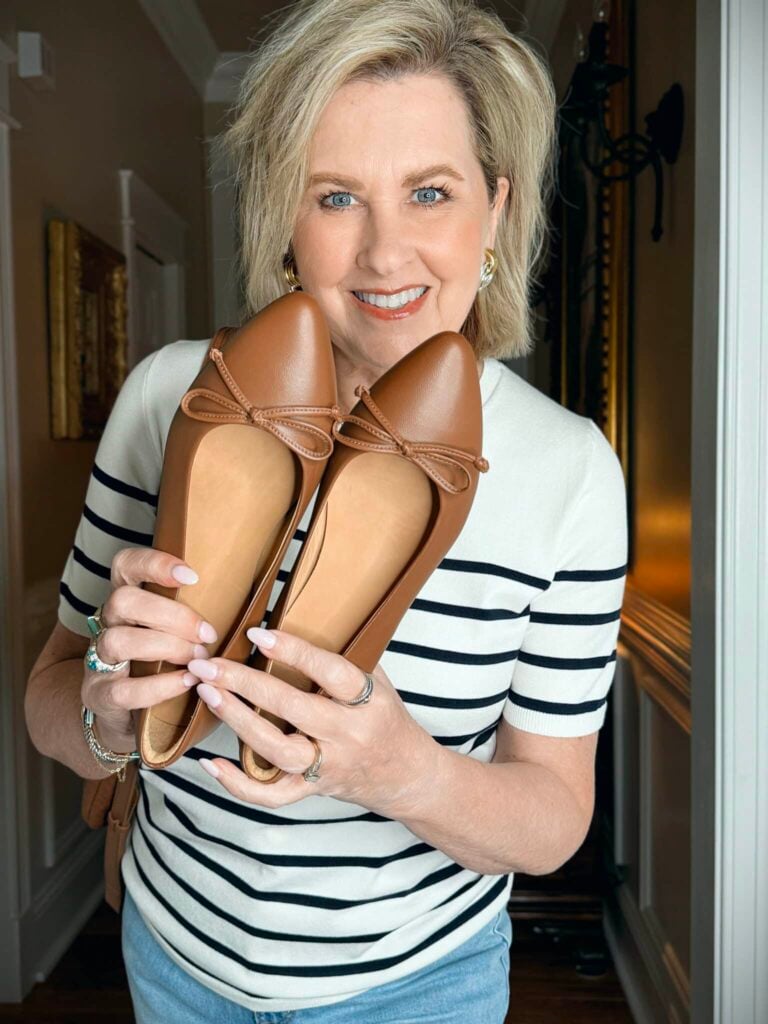 Tania holding a pair of caramel ballet flats with bows