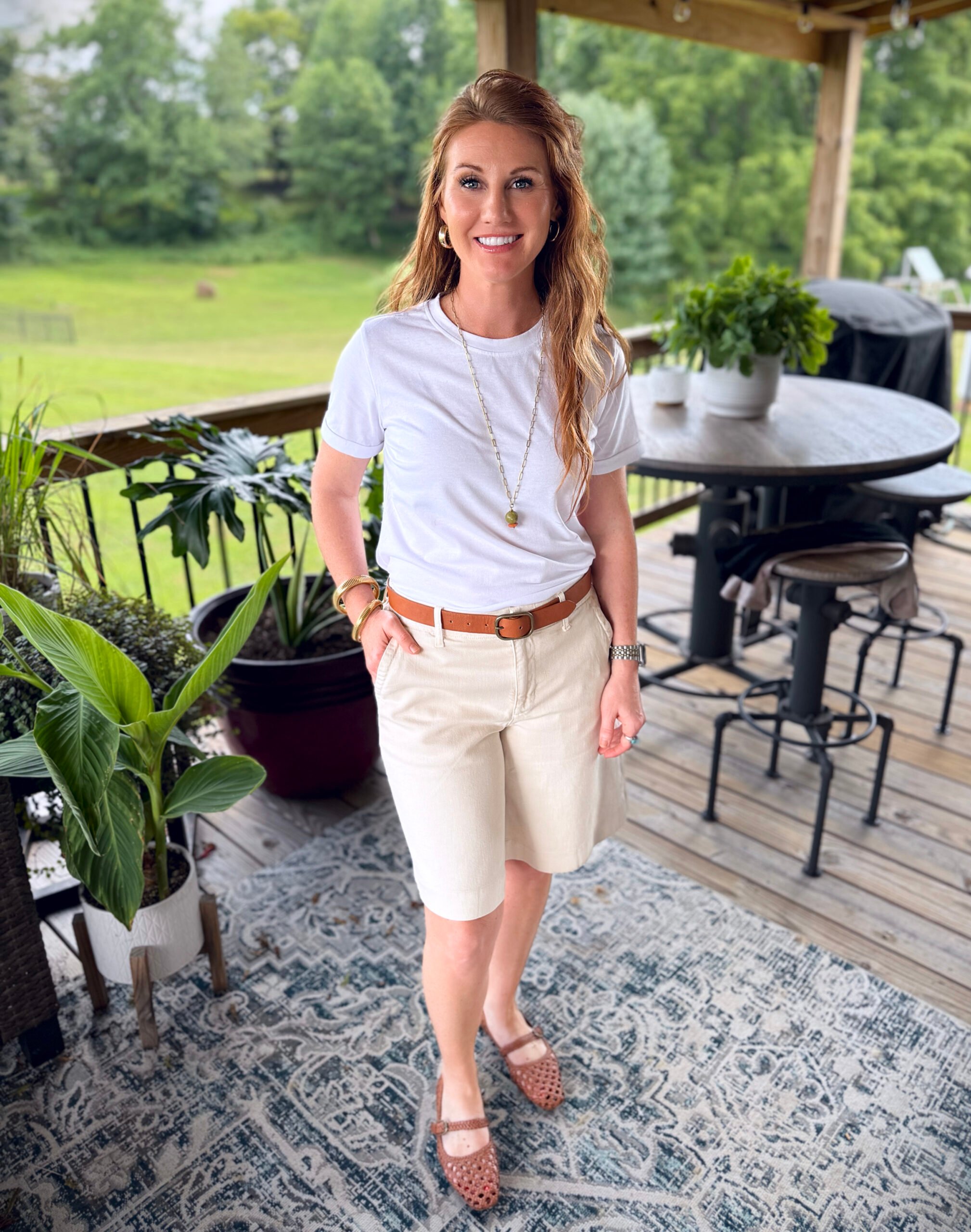 Stephanie, a petite 5'3" tall, wearing knee length beige shorts from Amazon with a white tee 