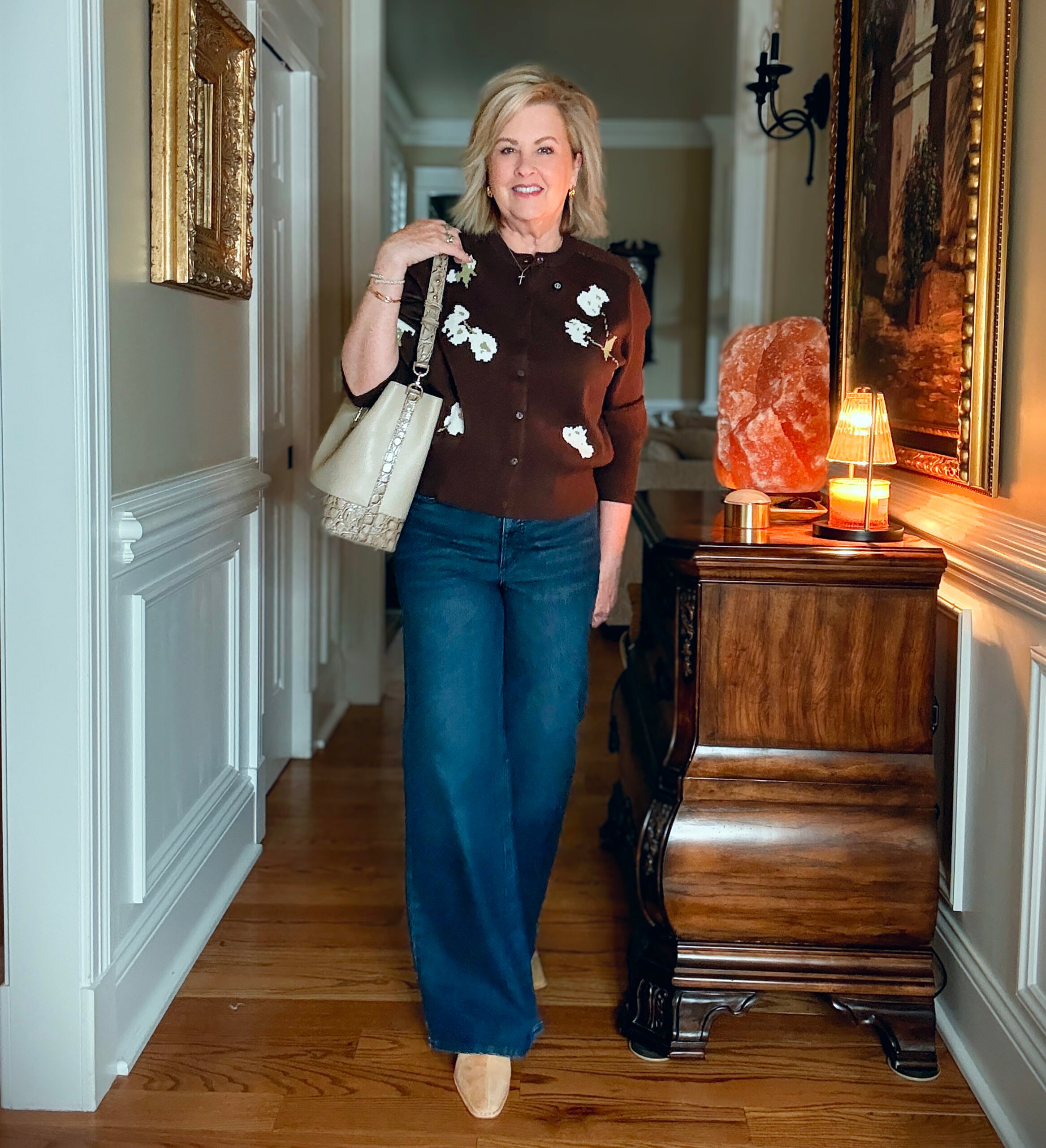 Tania is a dark brown sweater and dark wash jeans from Walmart. She is carrying a Brahmin handbag