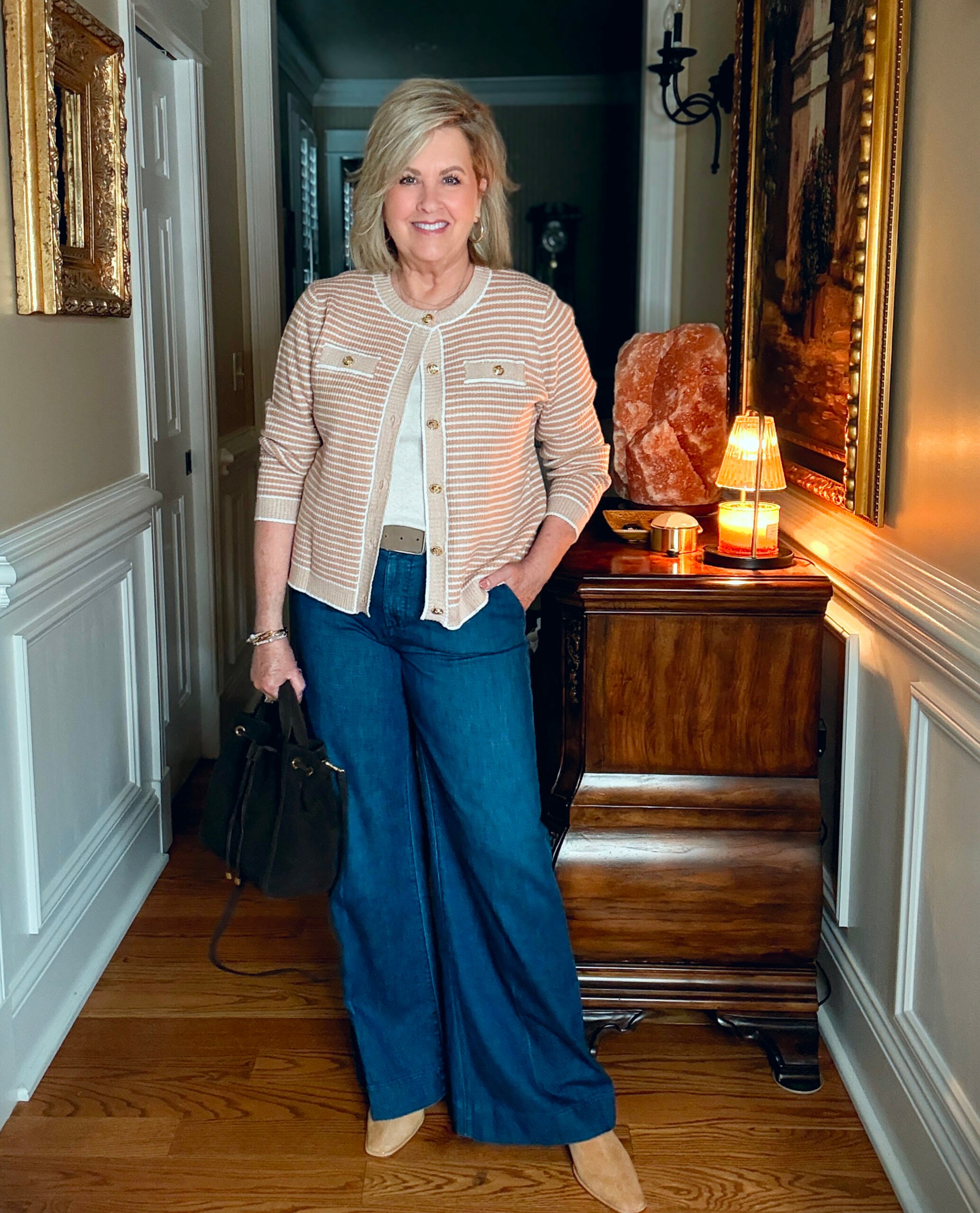 Tania is wearing a camel plaid jacket, a white tee, and wide leg jeans