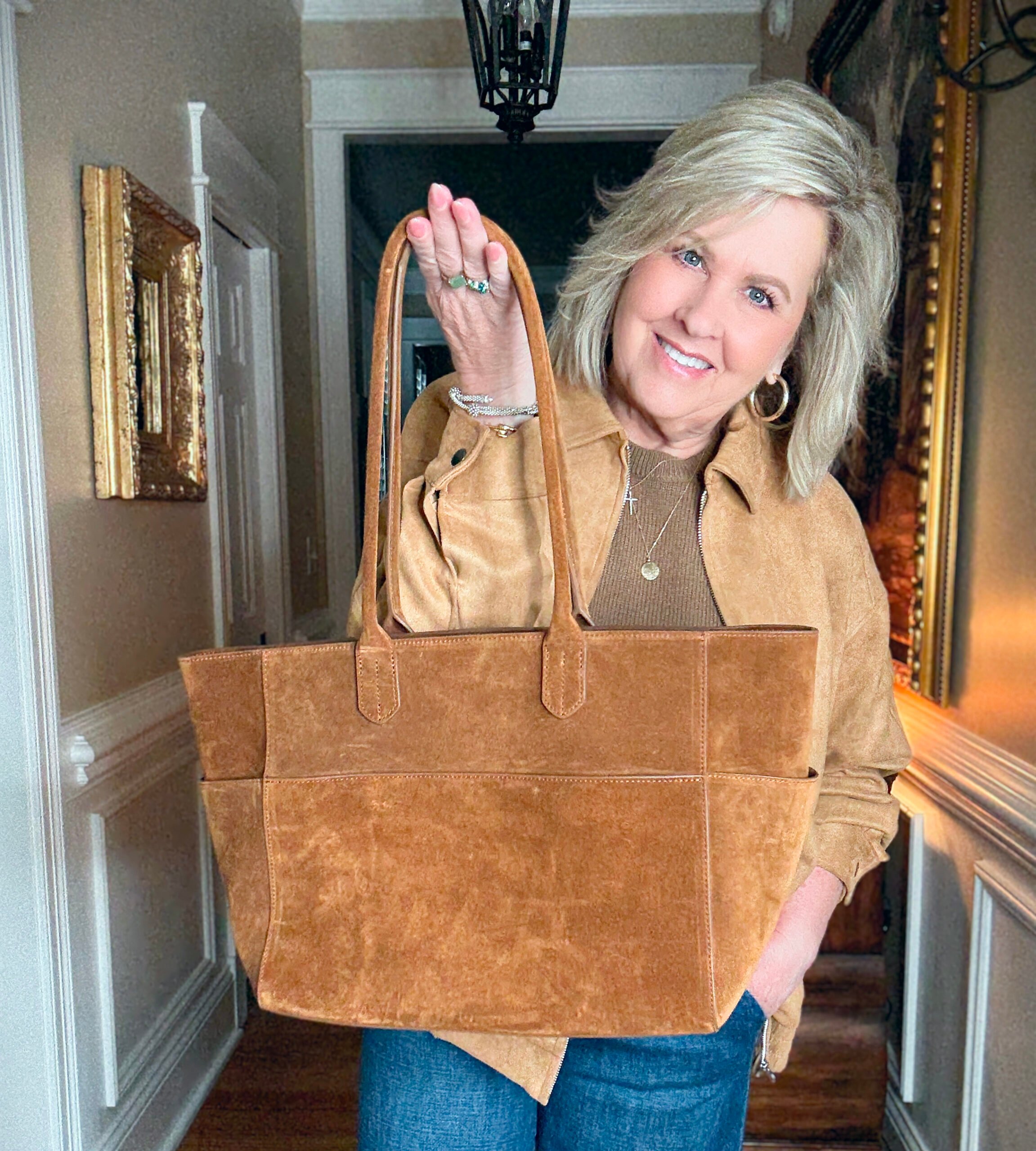Tania is wearing a camel jacket with a suede tote.