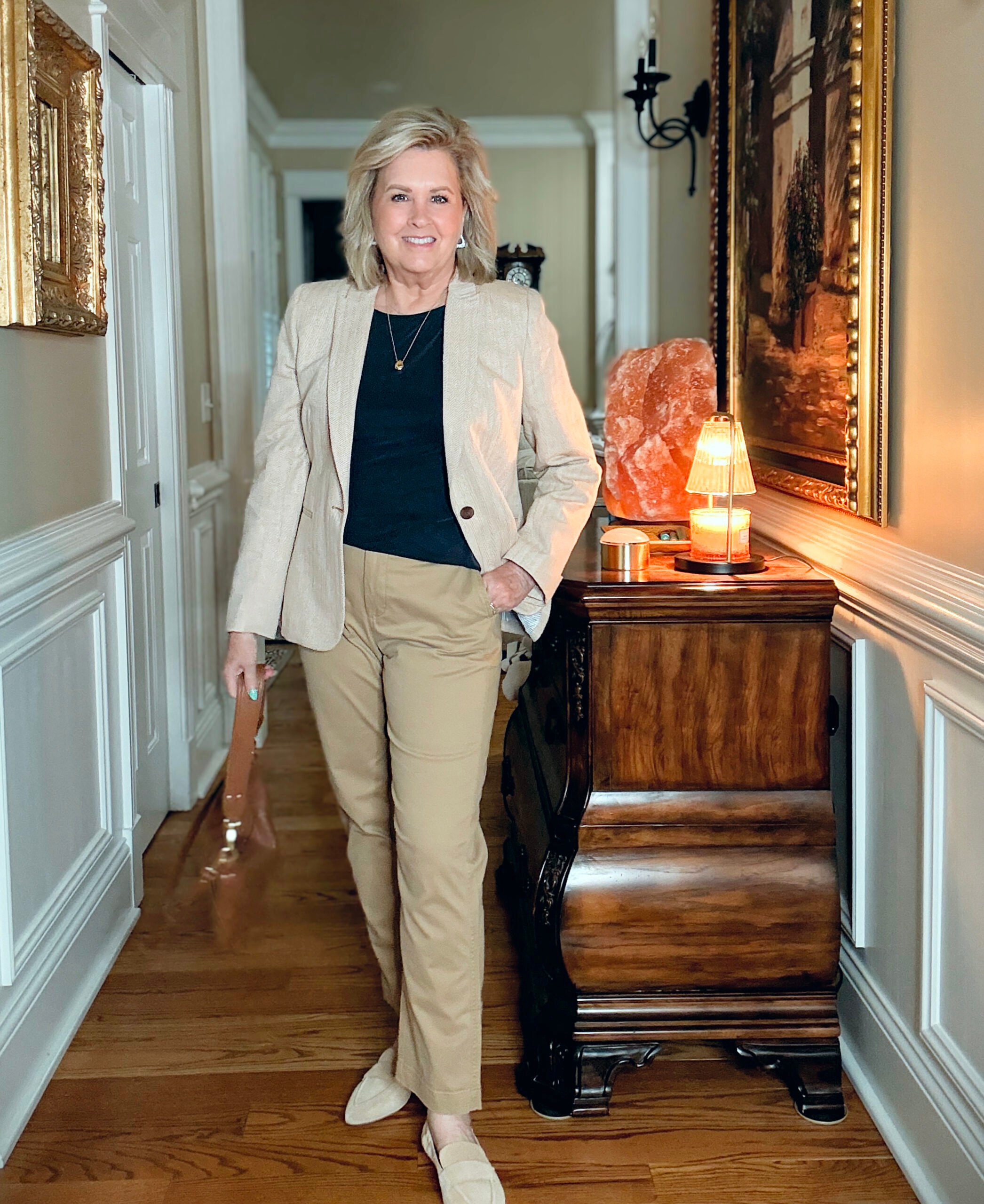 Tania Stephens in a hallway wearing a navy tee, a herringbone blazer, and a pair of chinos from J.Crew Factory