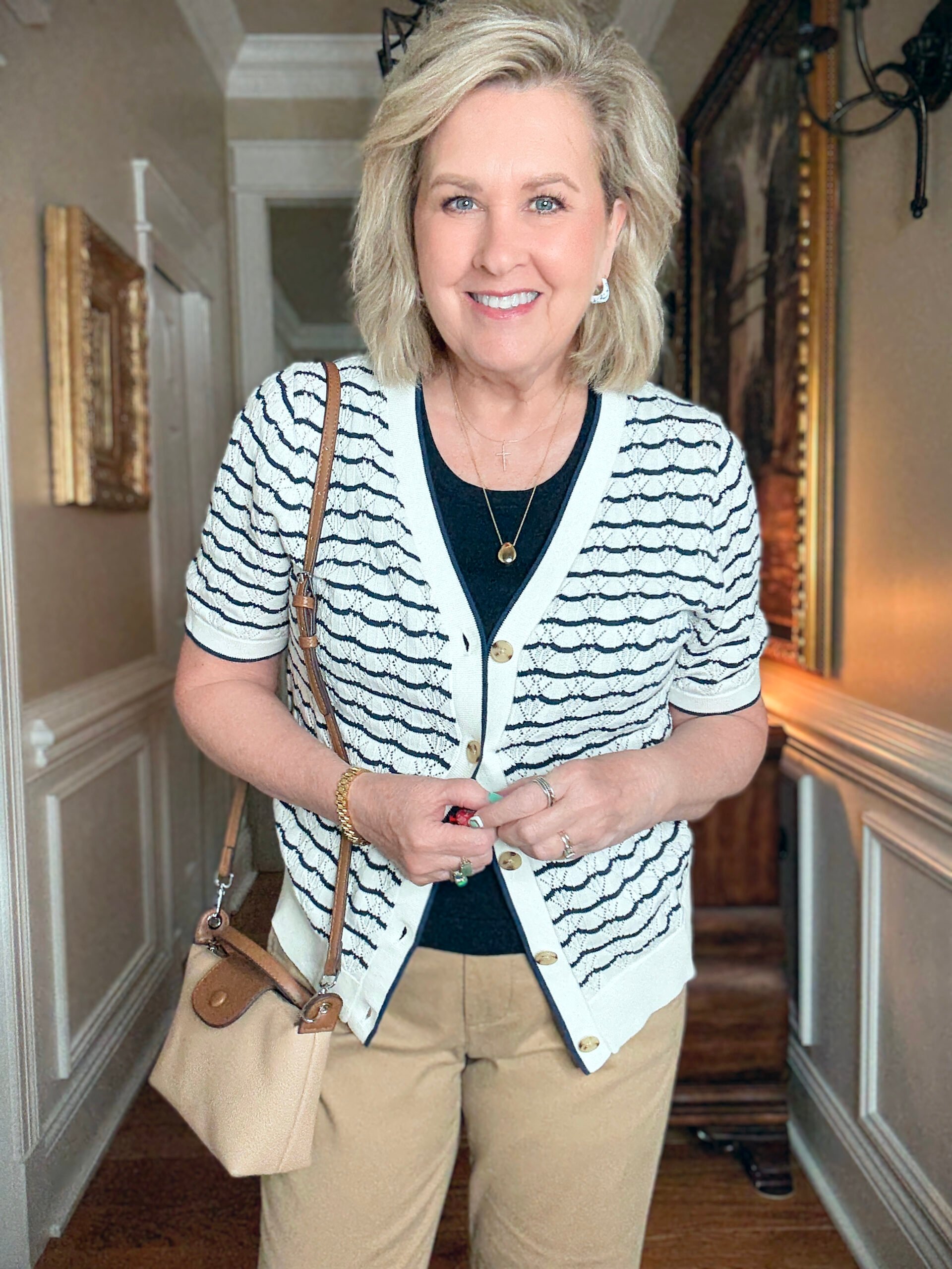 Tania Stephens in a hallway wearing a navy tee and a navy & white cardigan