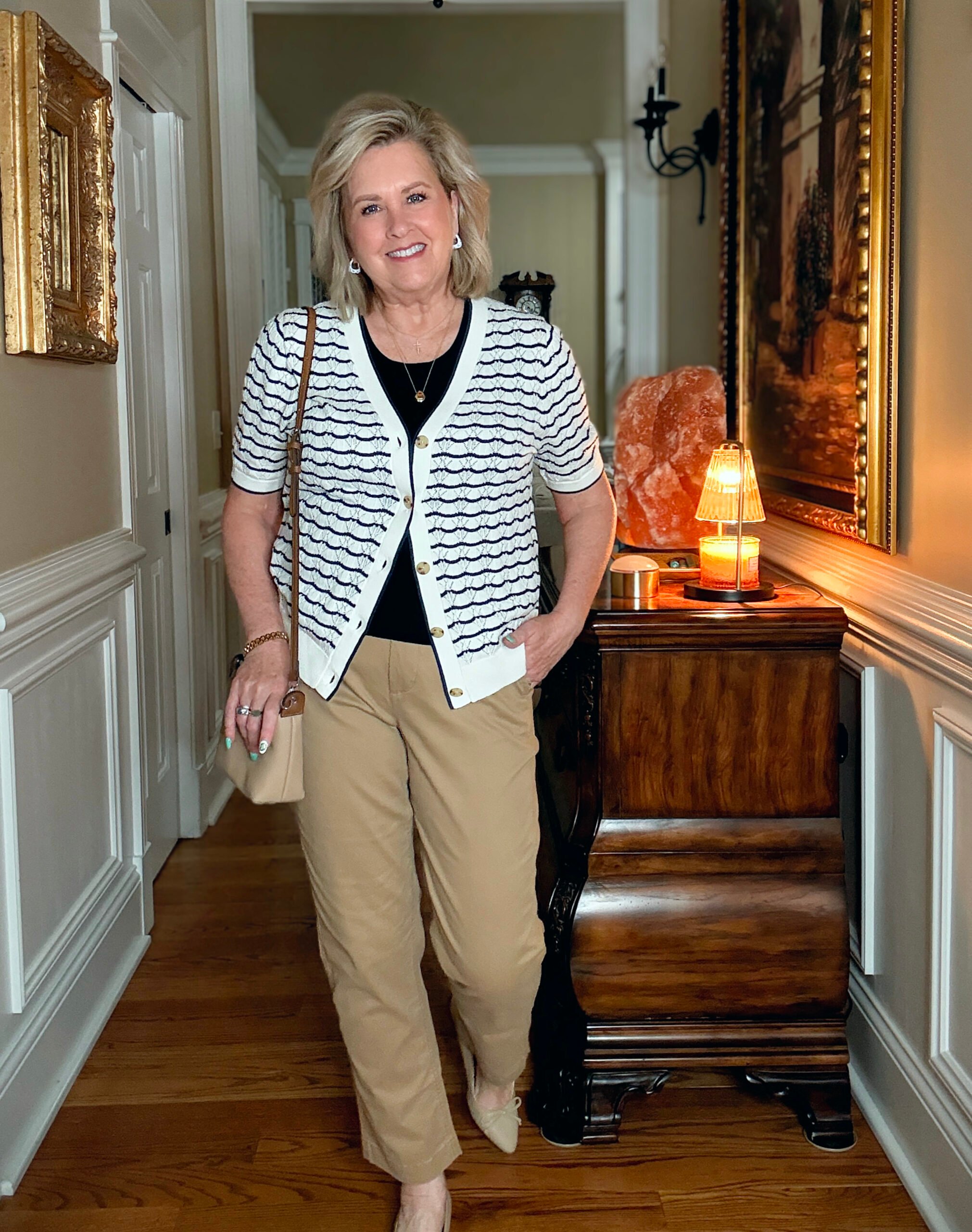 Tania Stephens in a hallway wearing a navy tee, a navy & white cardigan, and a pair of chinos from J.Crew Factory