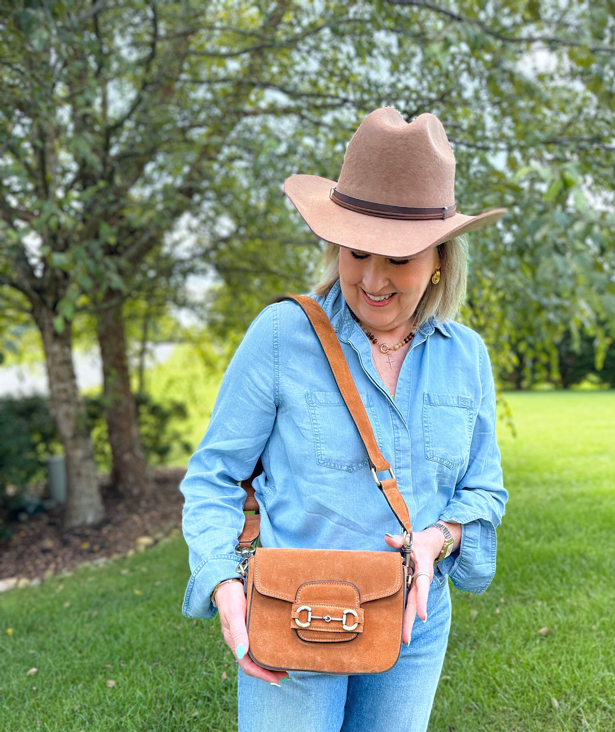 Black suede crossbody bag with horsebit detail styled in western-inspired fall look for women over 50.
