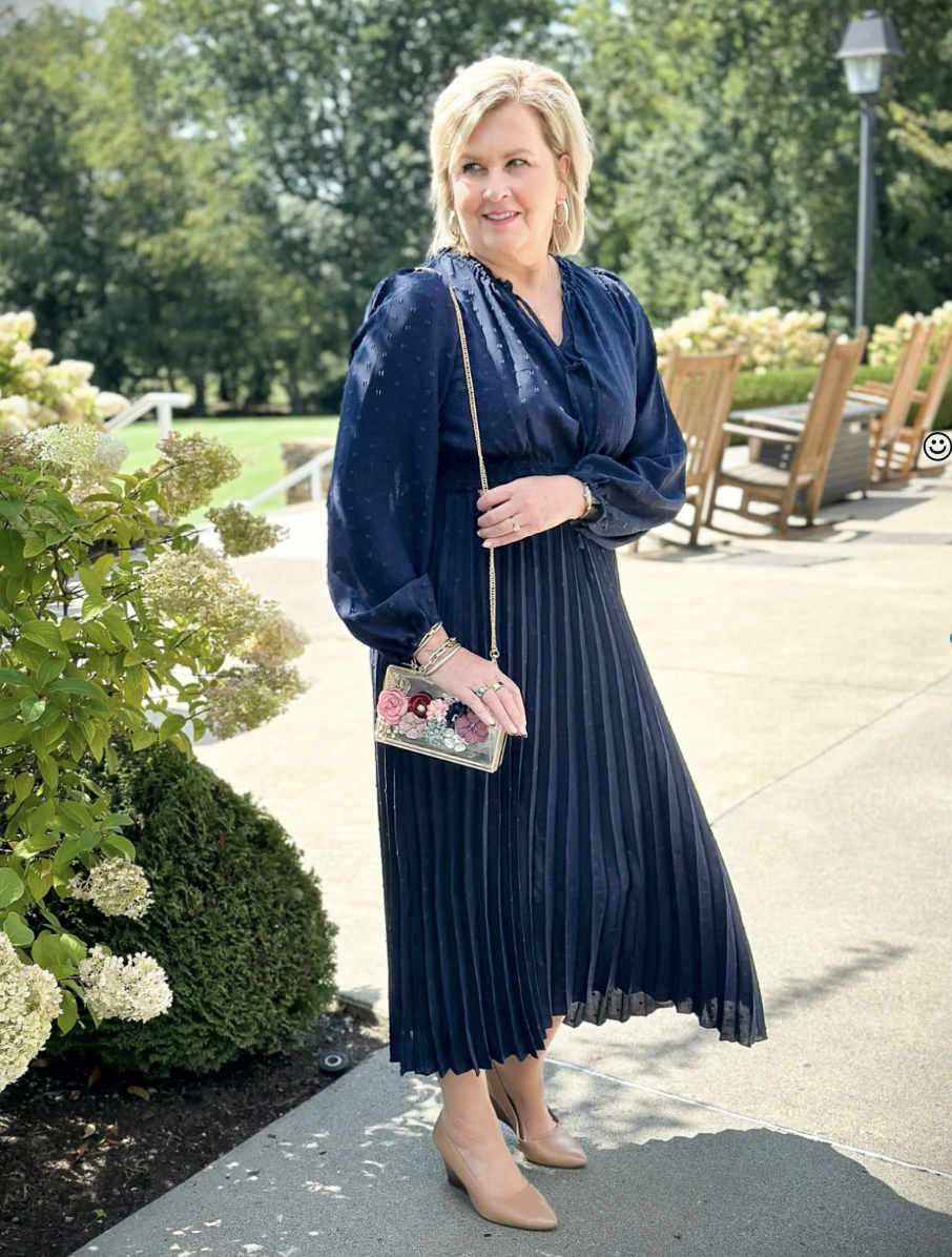 Fashion Blogger, Tania Stephens is styling fall wedding dresses for women over 50 - navy dress with pleated skirt