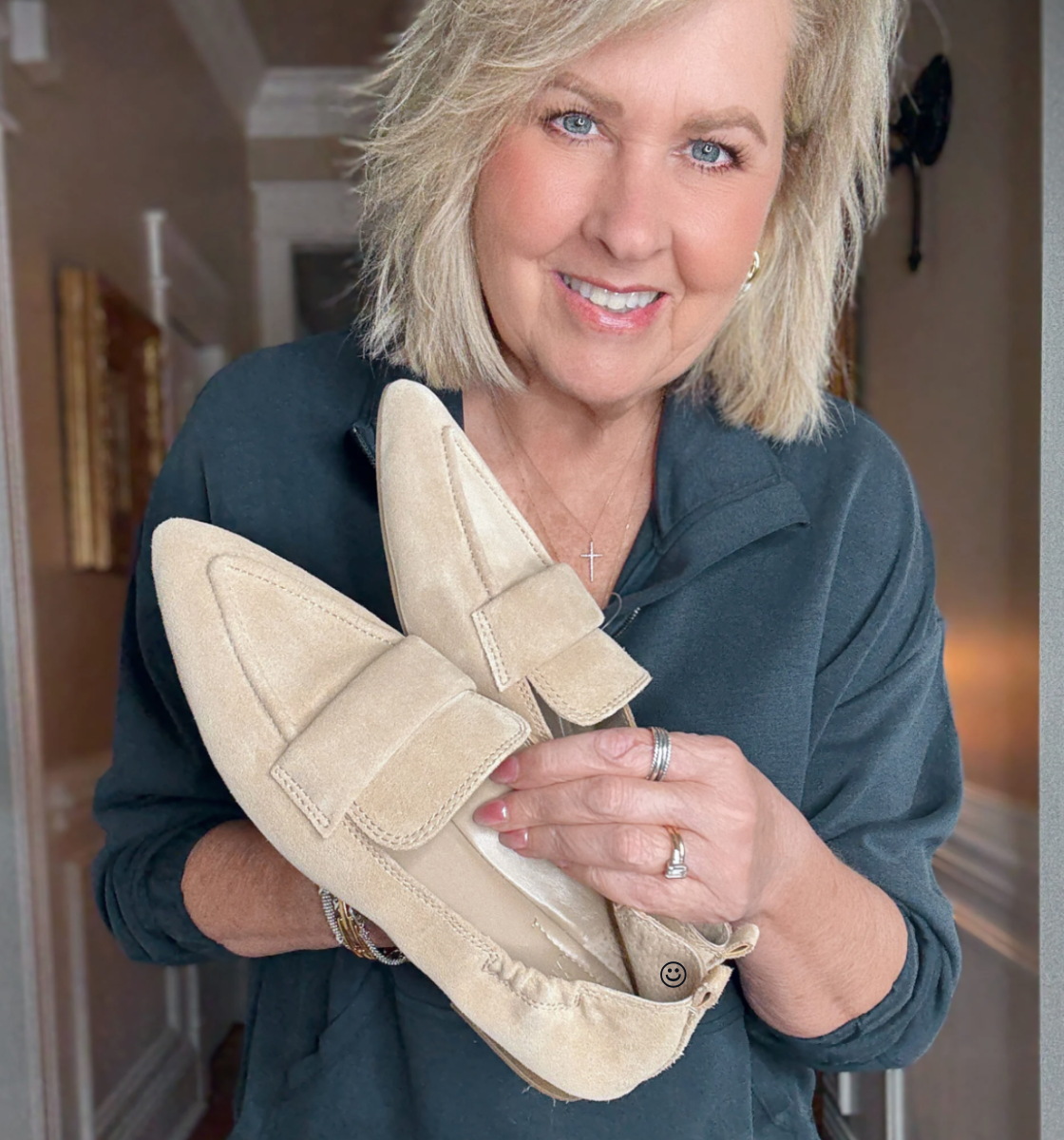 woman over 50 holding a pair of suede loafers
