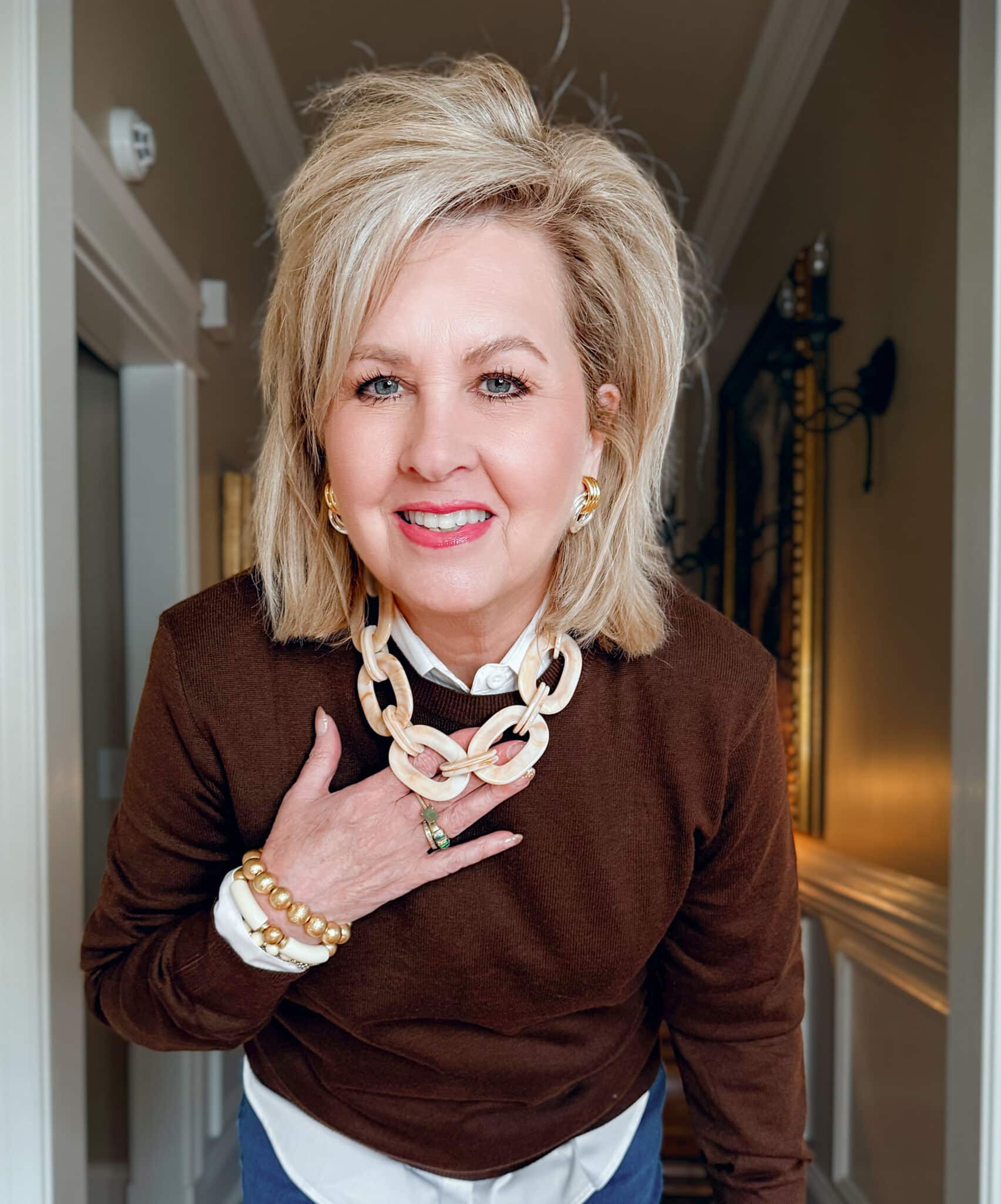 Tania is wearing an Amazon Brown Sweater with a White Button Down Shirt with lucite necklace