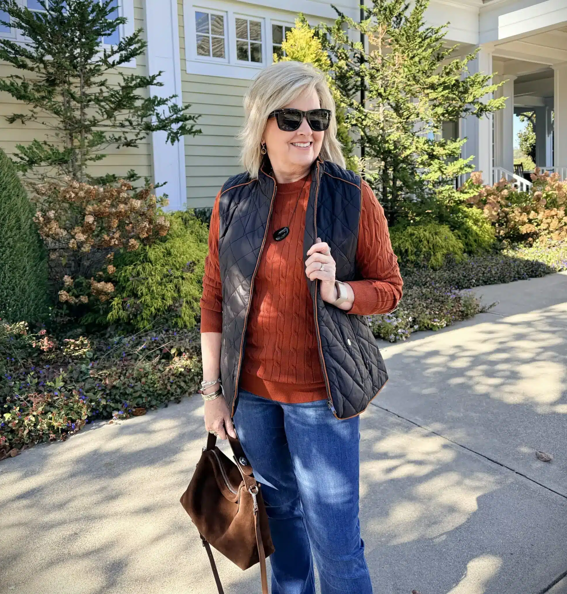 BLONDE WOMAN STYLING A CABLE KNIT SWEATER UNDER A VEST 