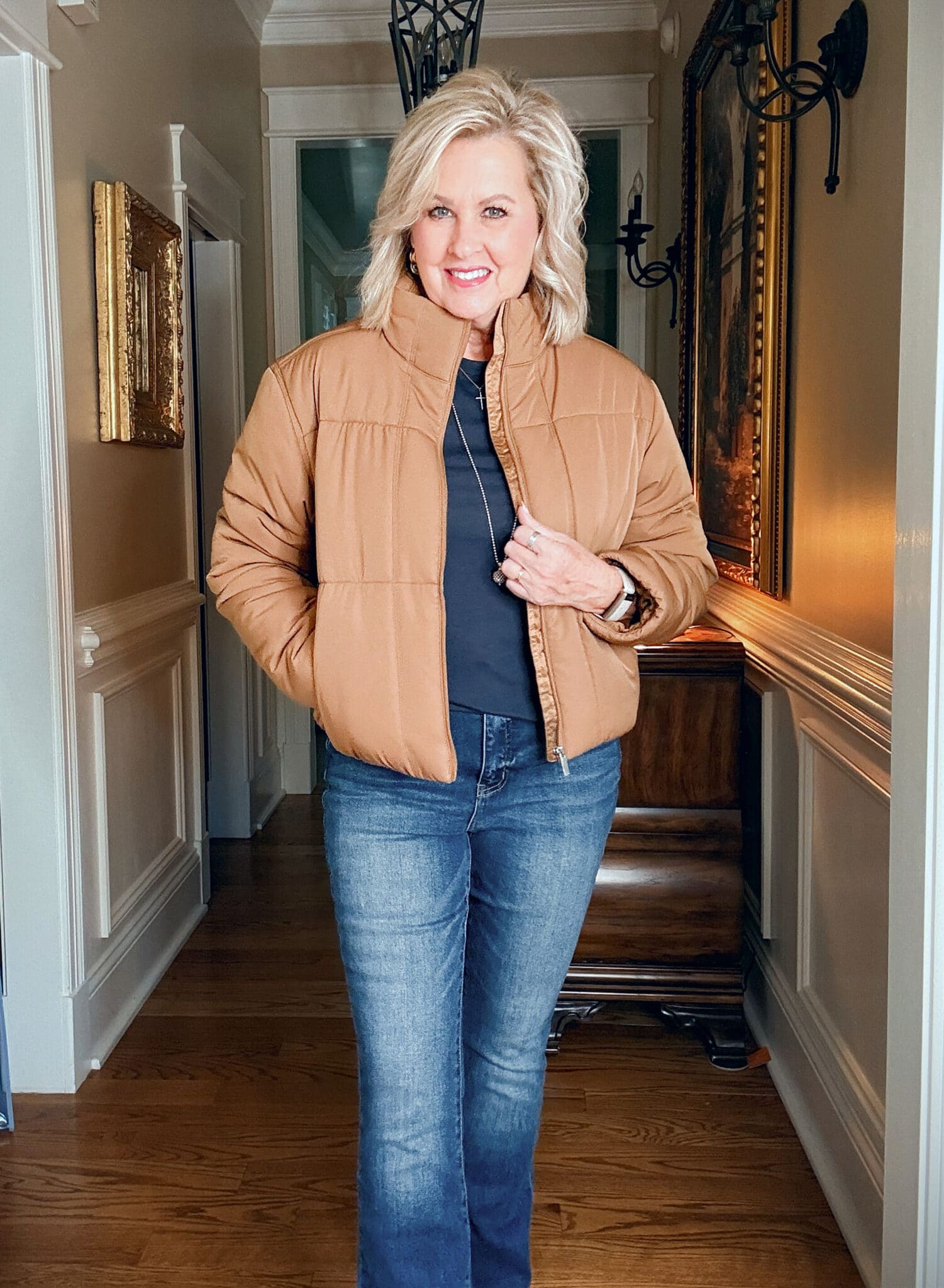 Tania wearing a navy tee and jeans with a caramel short puffer jacket from  Travis Mathews